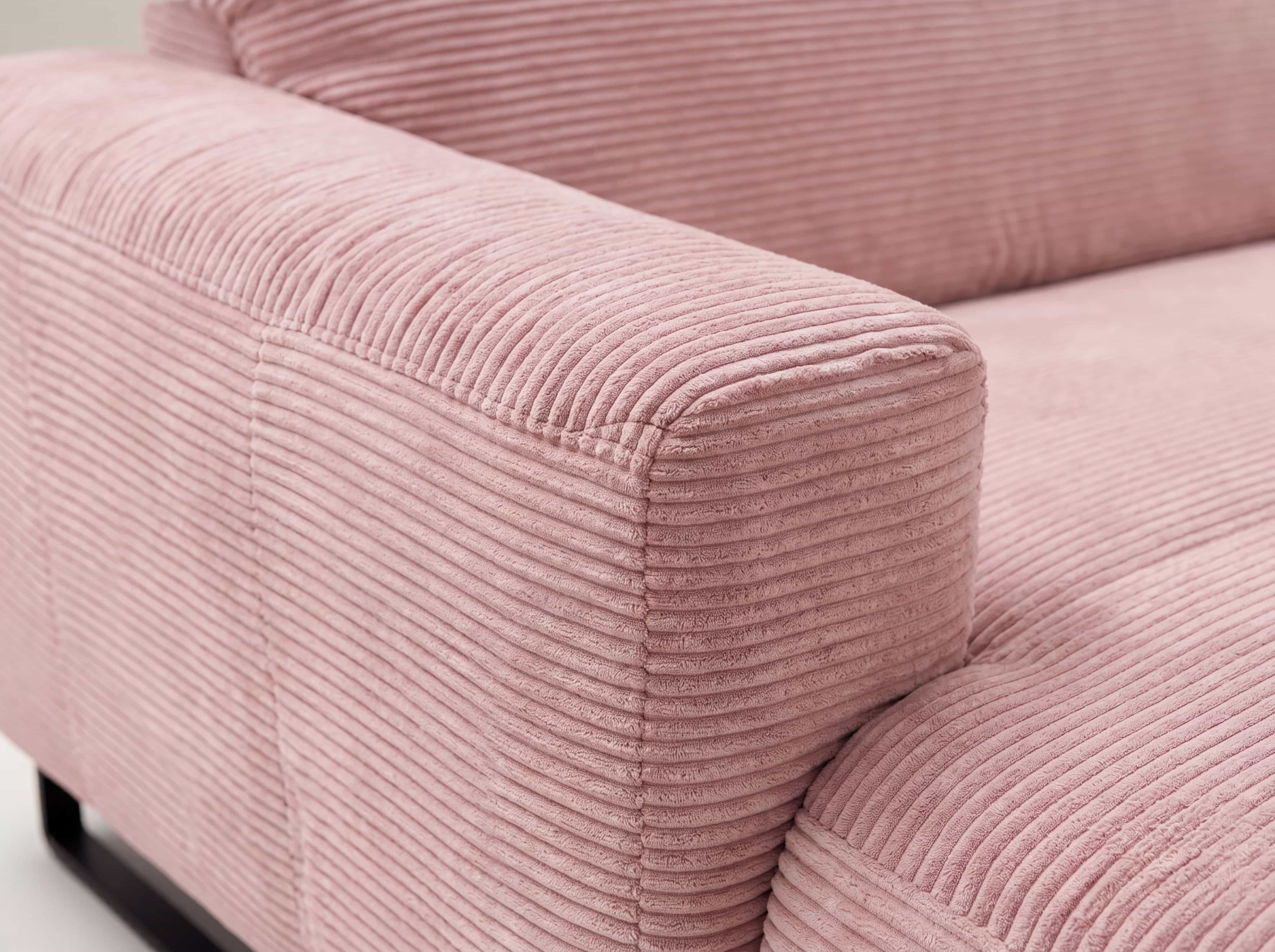 Ecksofa Calvene – Detailansicht des rosa Cordbezugs mit Armlehne und markanter Rippenstruktur