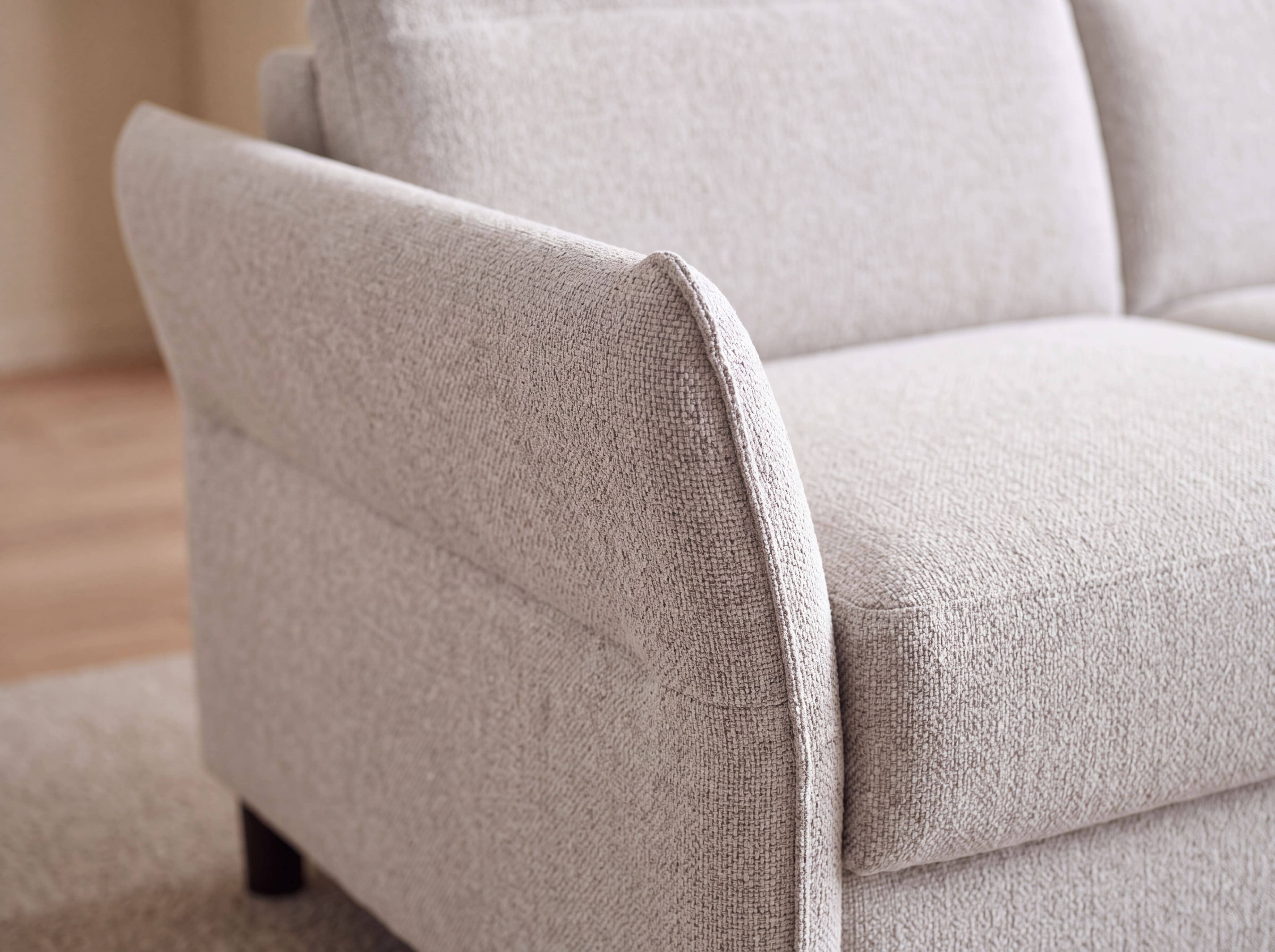 2-Sitzer Sofa mit beigefarbenem Stoffbezug, gepolsterter Sitzfläche und abgerundeter Armlehne