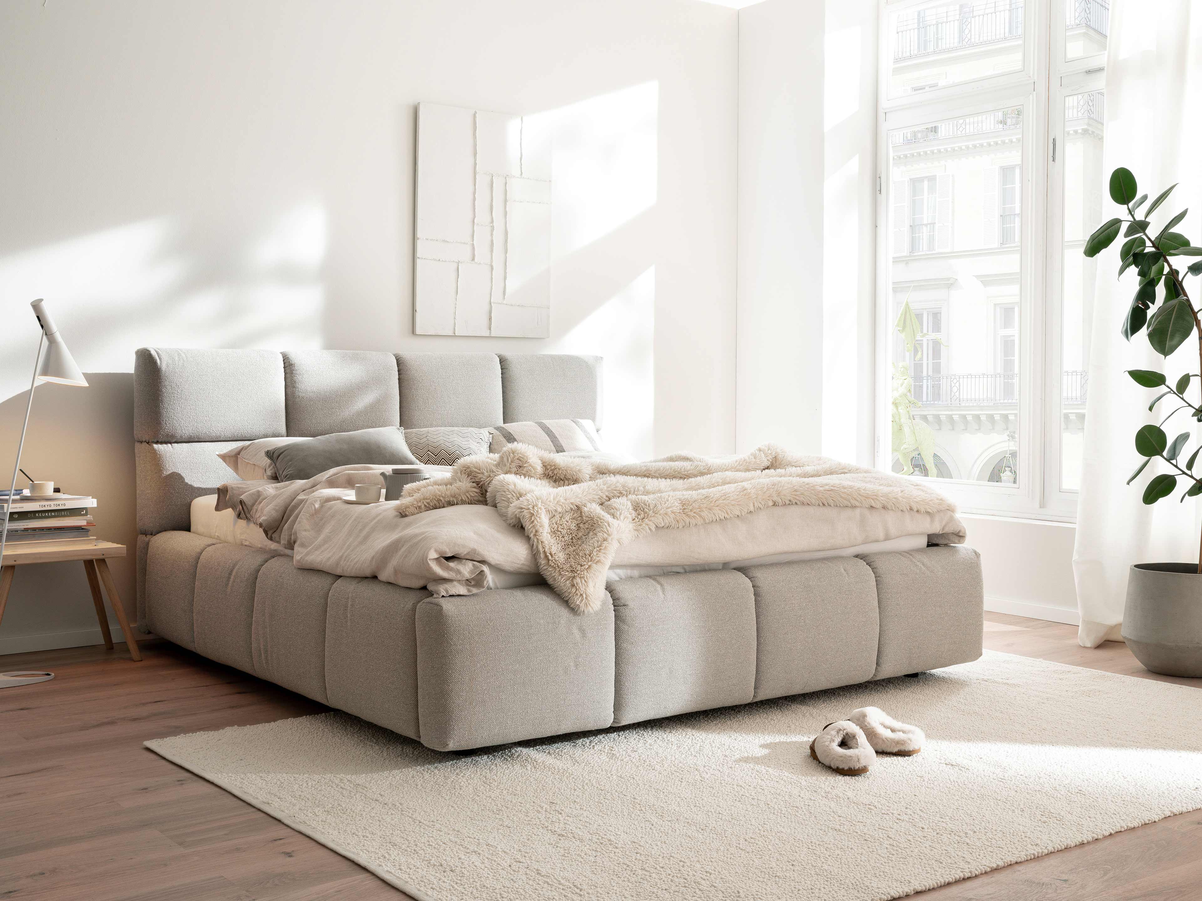 Boxspringbett Kabs in hellgrauem Stoff mit gepolstertem, segmentiertem Kopfteil und weichem Rahmen