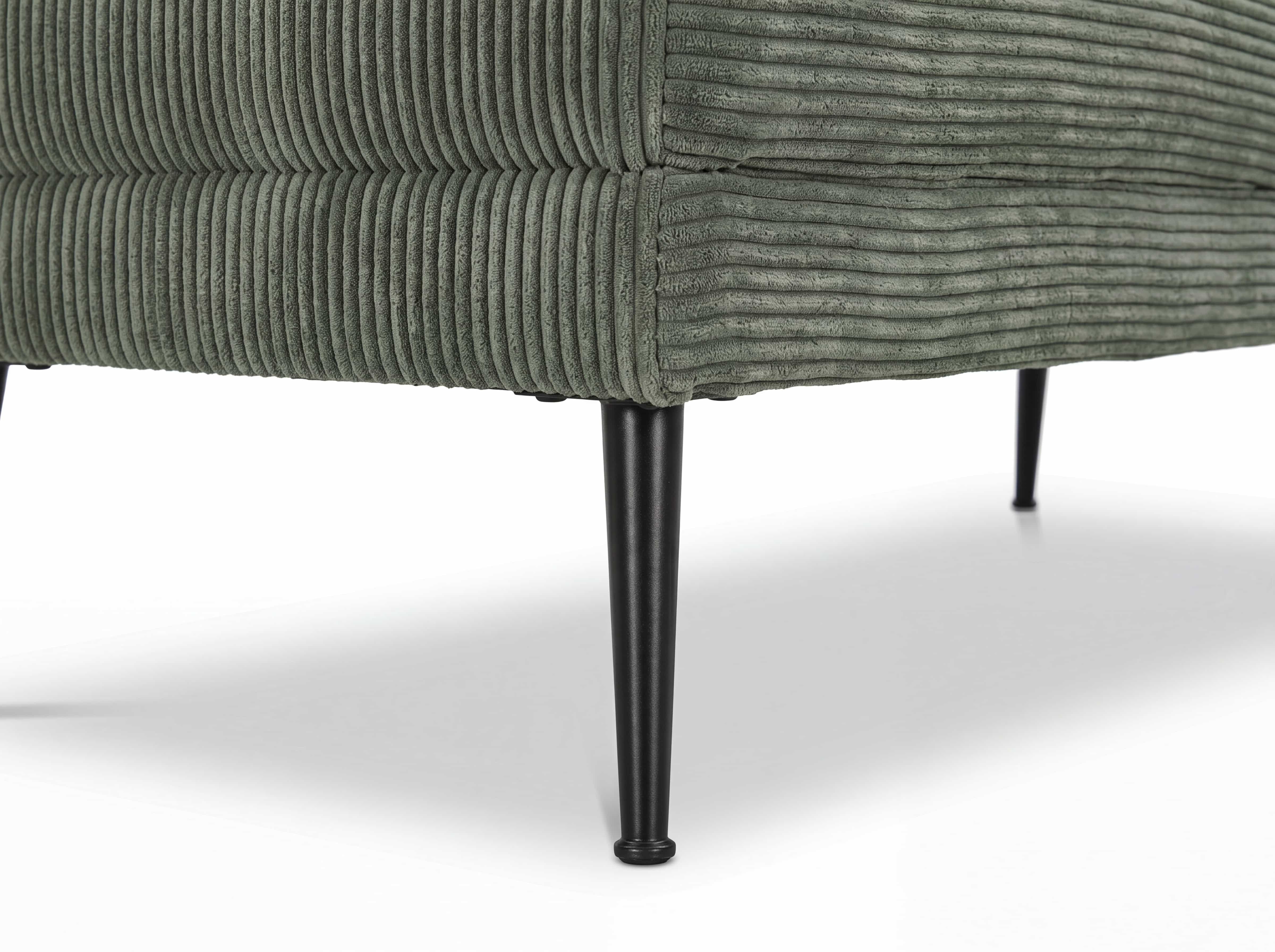 Detailansicht eines Sofas mit grünem Cordbezug und schwarzen, schlanken Metallfüßen.