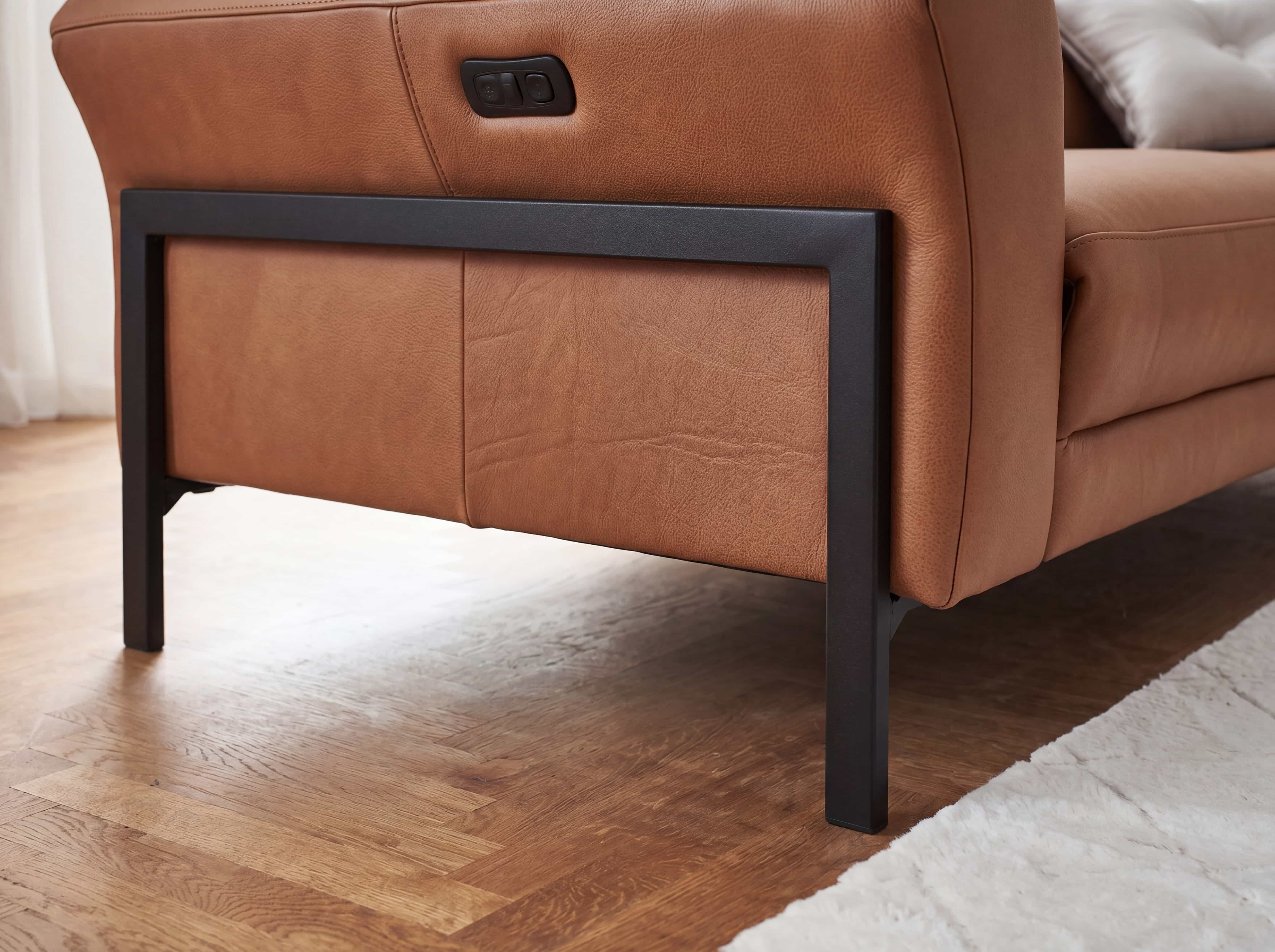 Ecksofa mit cognacfarbenem Lederbezug, sichtbarem schwarzen Metallgestell und elektrischer Steuerung