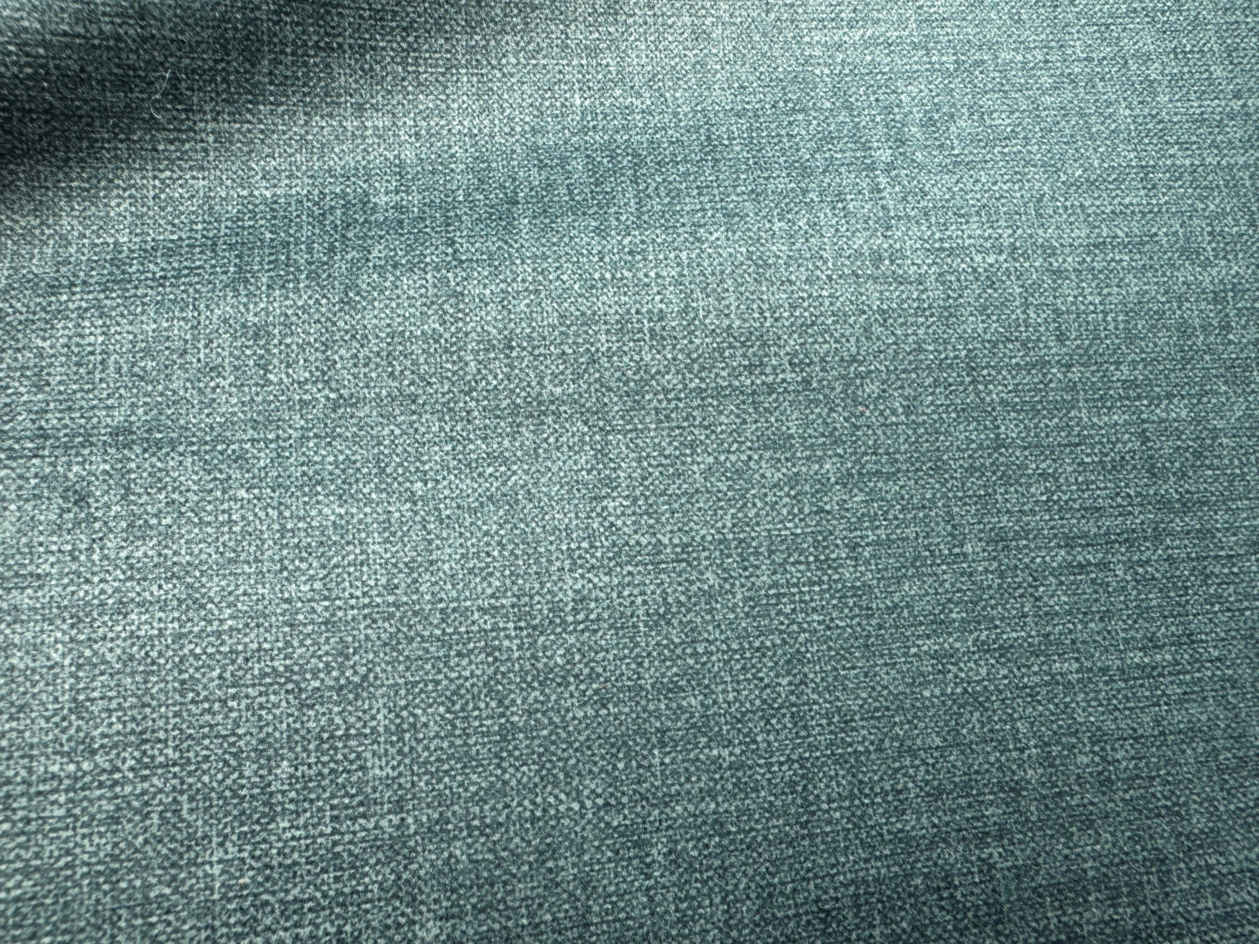 Detailaufnahme eines strukturierten, blau-grauen Stoffbezugs mit feiner, leicht melierter Oberfläche