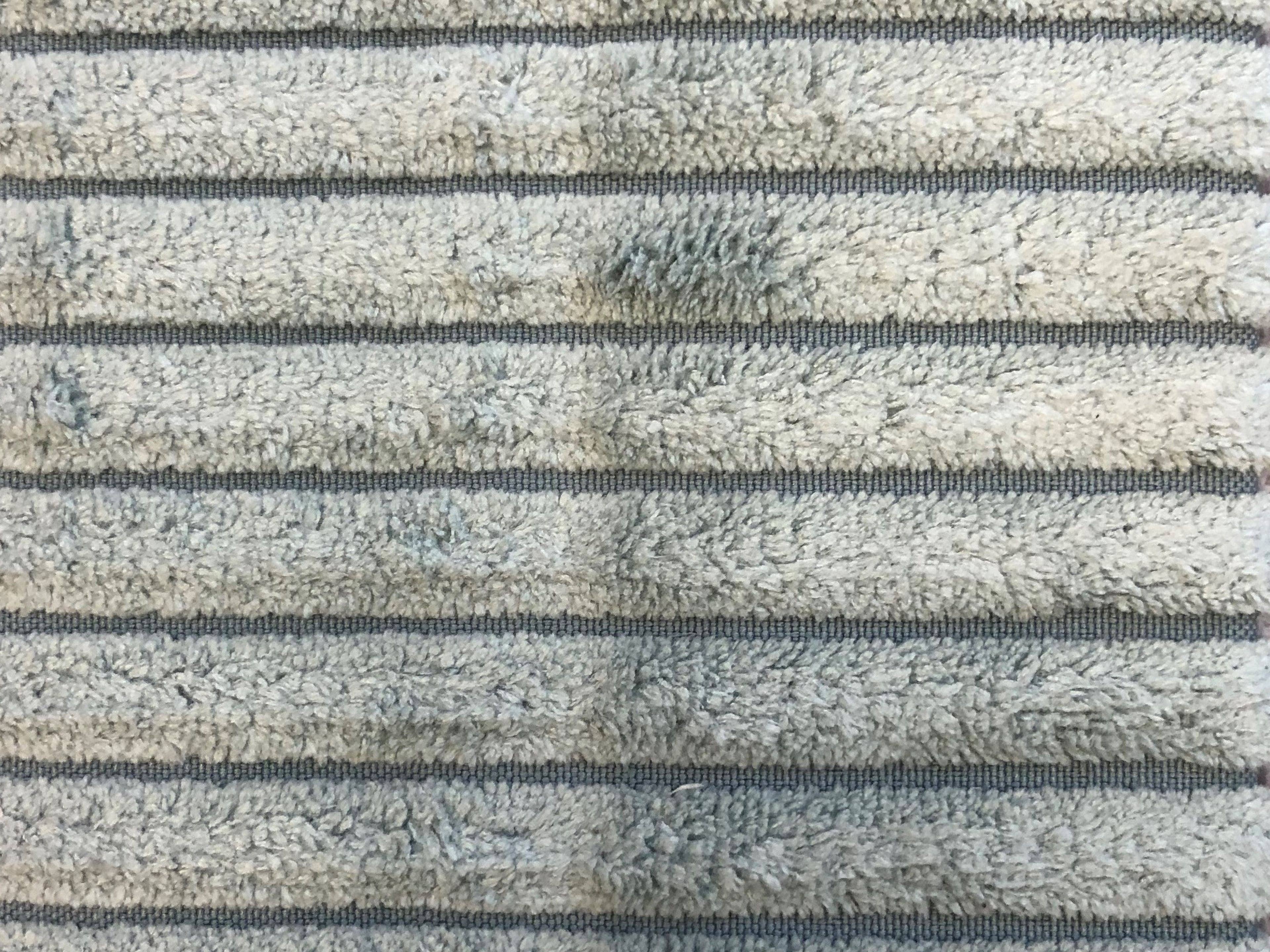 Hellgrauer Teppich aus weichem Hochflor mit regelmäßigen quer verlaufenden Streifen in Dunkelgrau