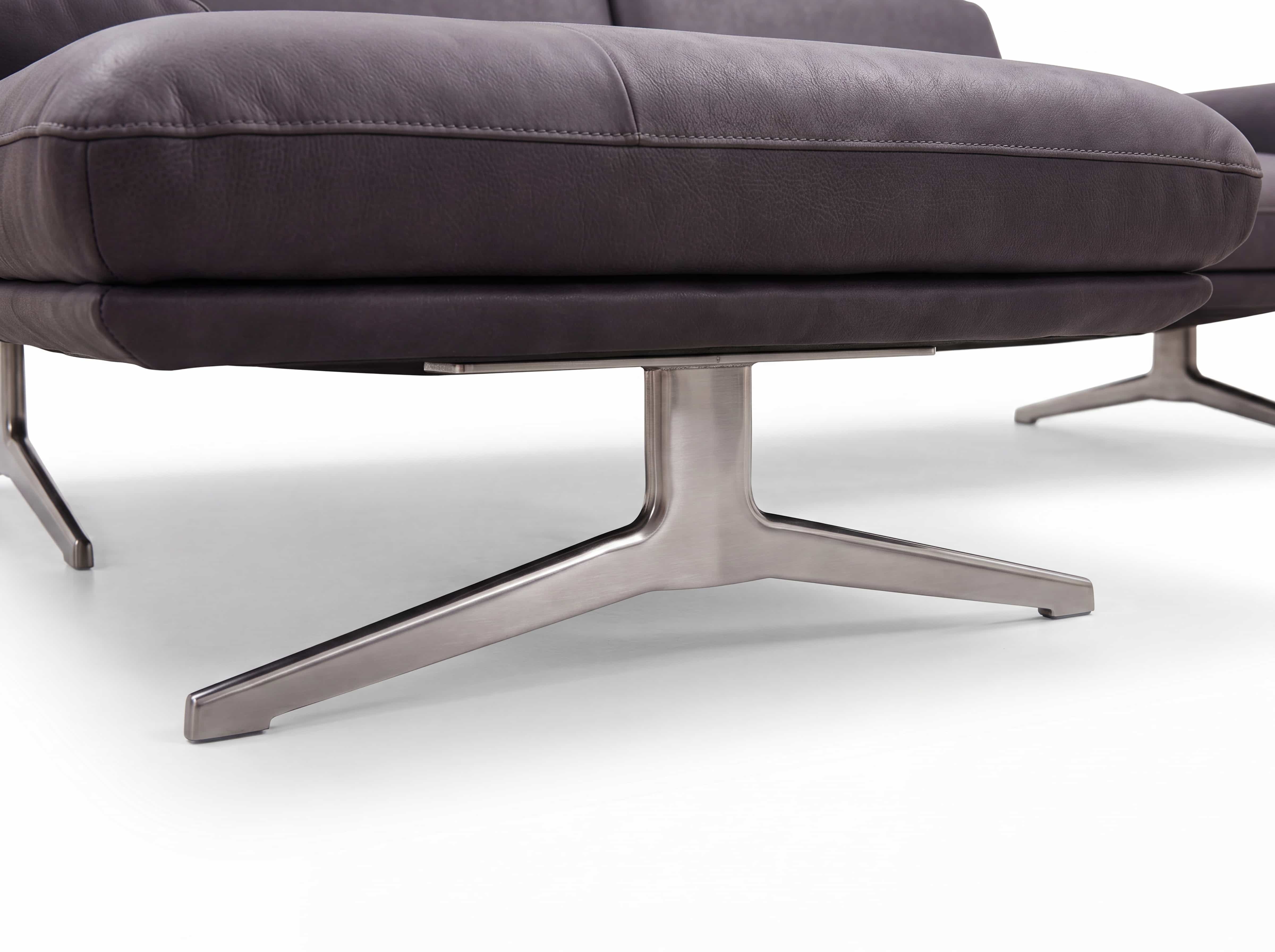 Sofa mit dunkelgrauem Lederbezug und markantem, gebürstetem Metallfuß in Y-Form