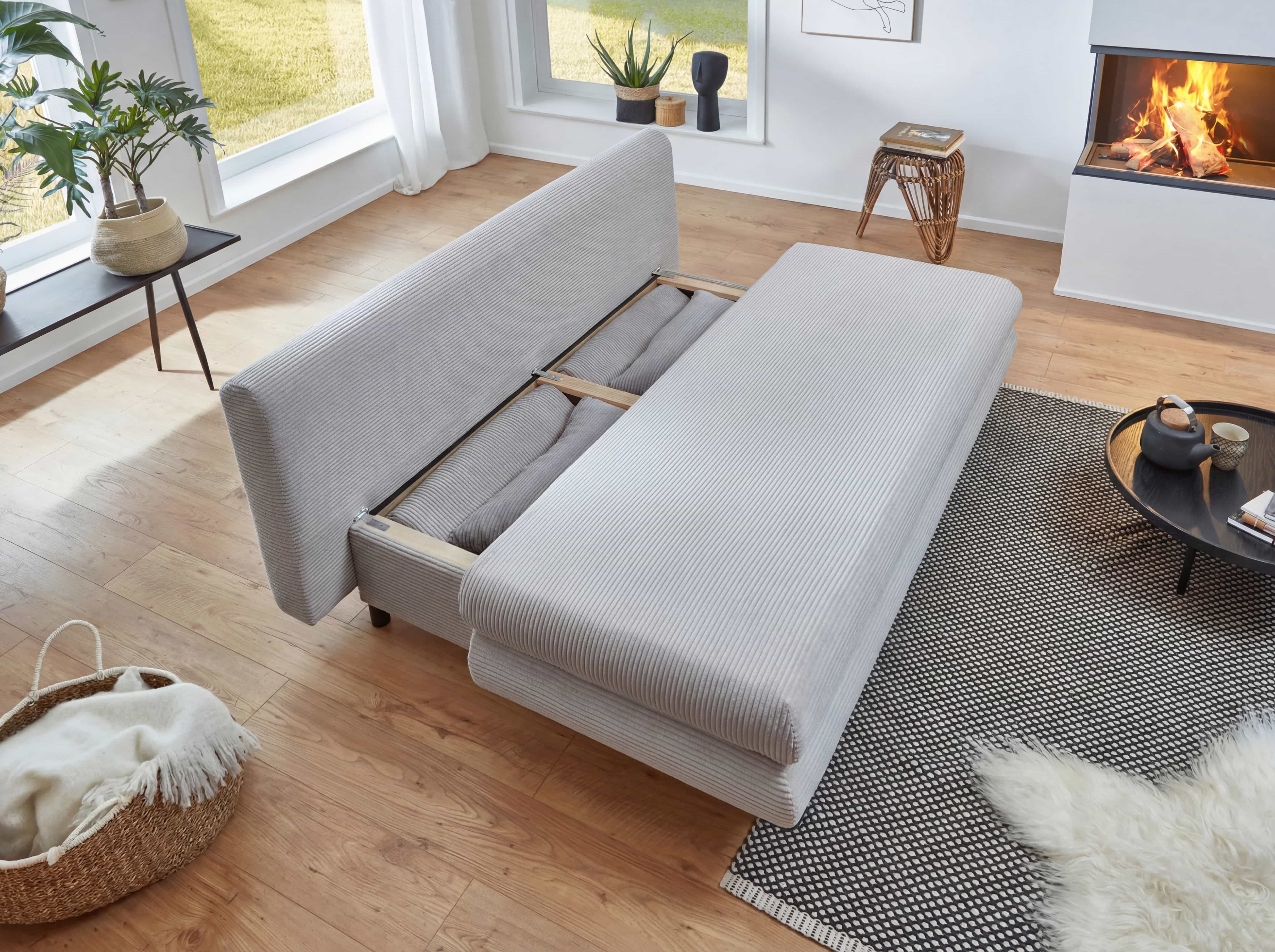 Schlafsofa mit hellgrauem Cordbezug, klappbar, mit sichtbarem Stauraumfach unter der Sitzfläche.