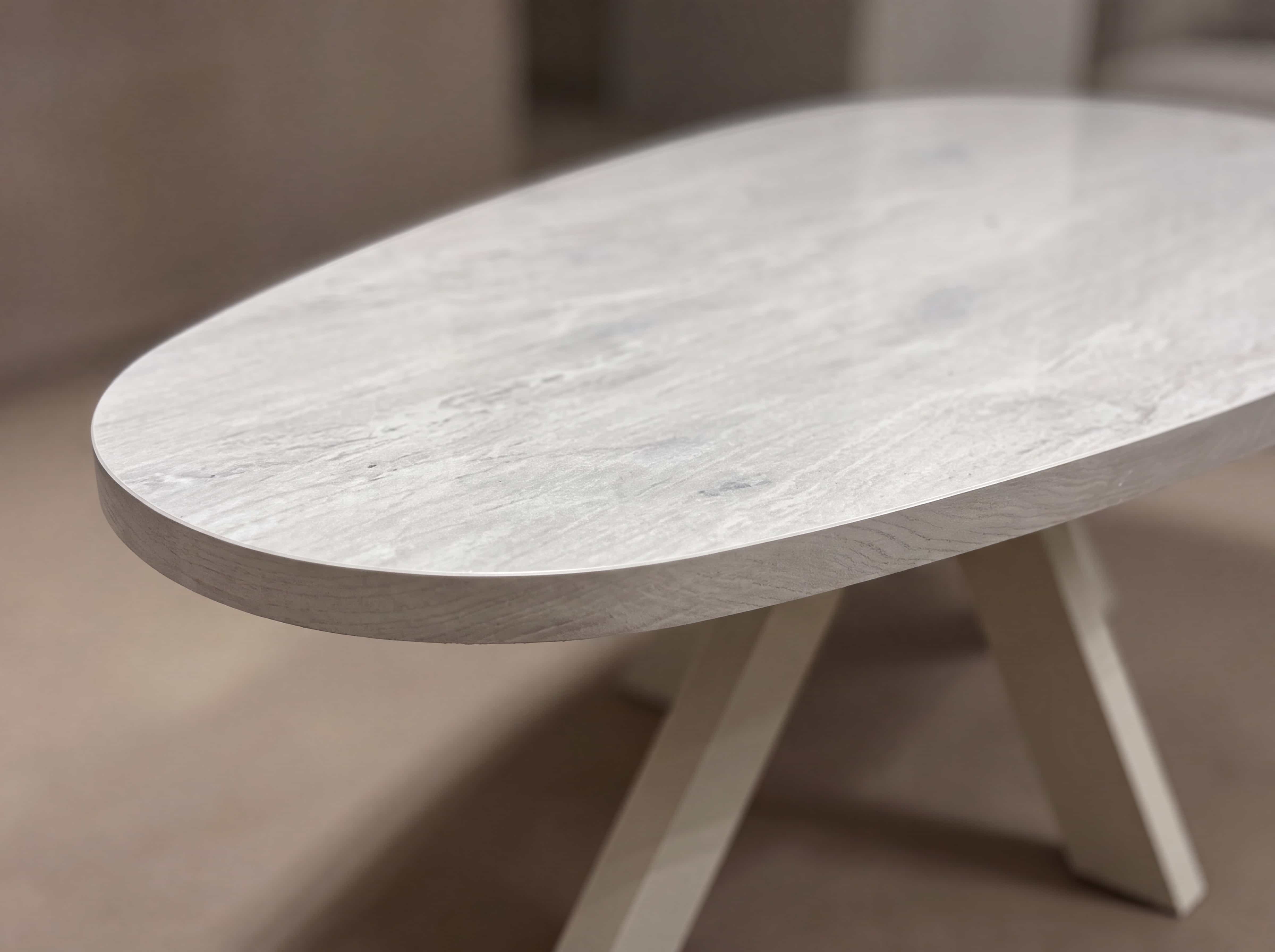 Couchtisch Somal – ovale, helle Tischplatte in Steinoptik mit schrägem Gestell in ähnlicher Farbe