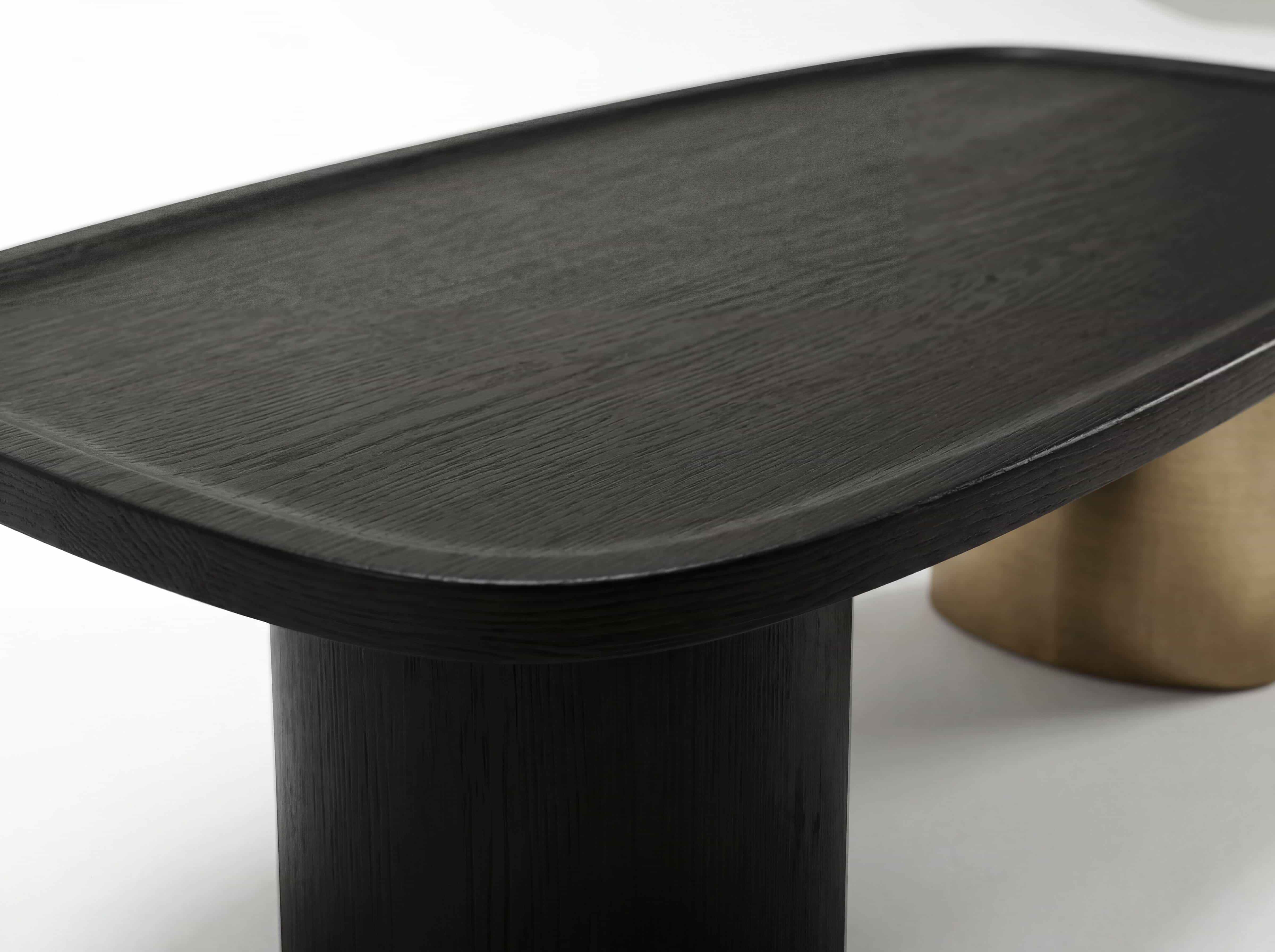 Couchtisch mit ovaler, abgerundeter Tischplatte aus dunklem Holz und zylindrischem Tischbein