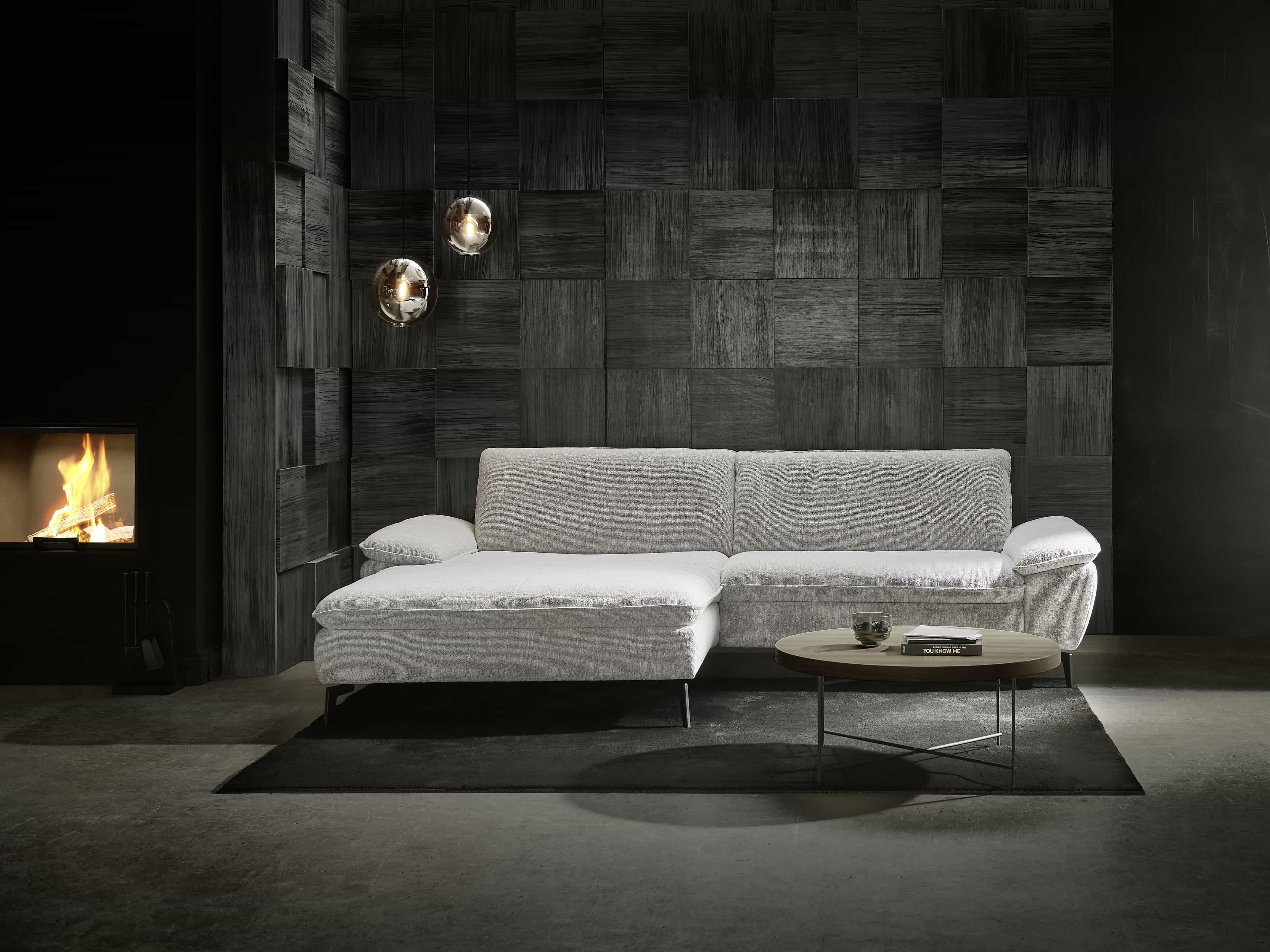 Ecksofa mit hellgrauem Stoffbezug, breiten Armlehnen und sichtbaren schwarzen Metallfüßen