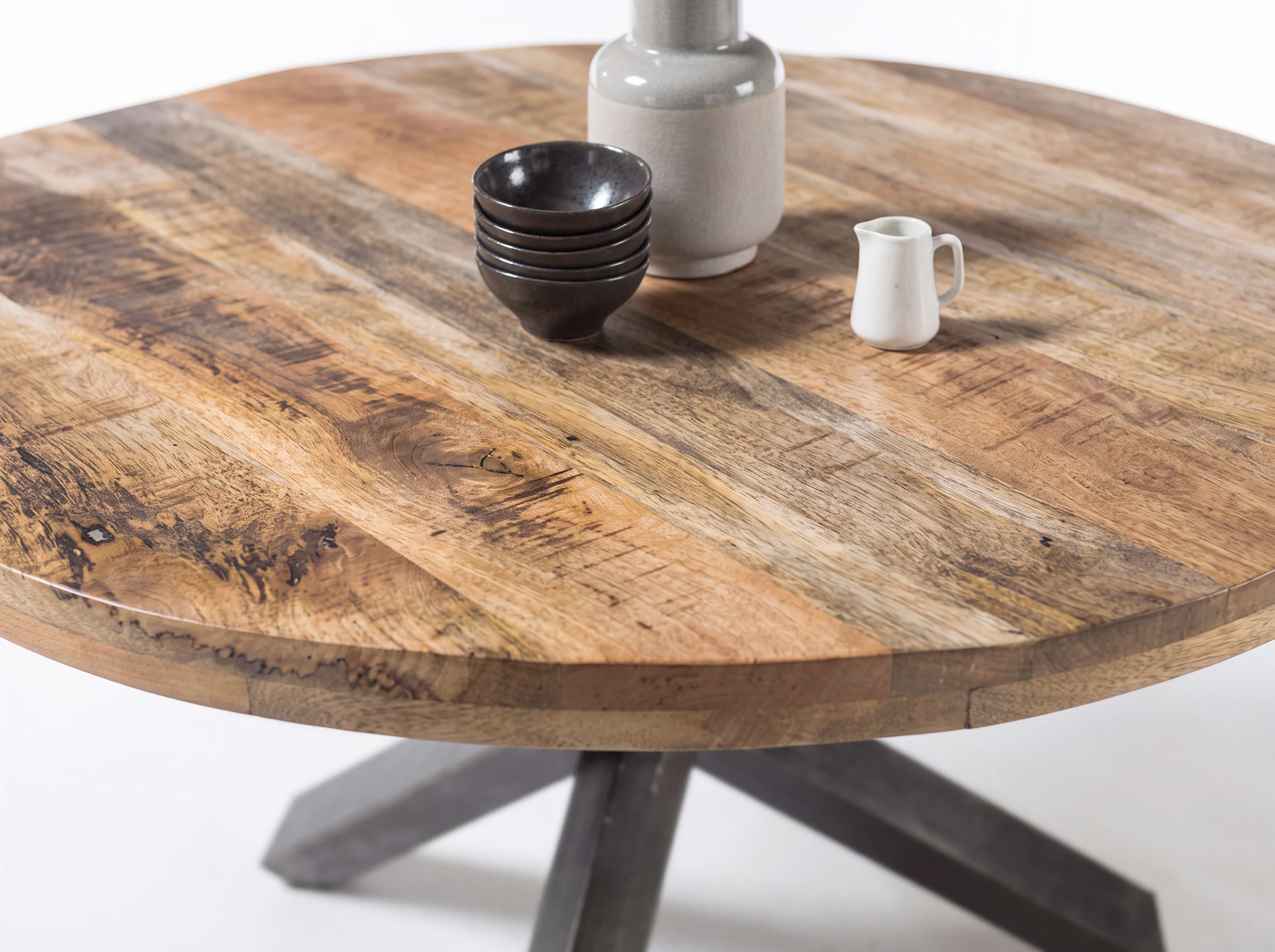 Runder Esstisch aus Massivholz mit naturbelassener Holzmaserung und schwarzem Kreuzgestell