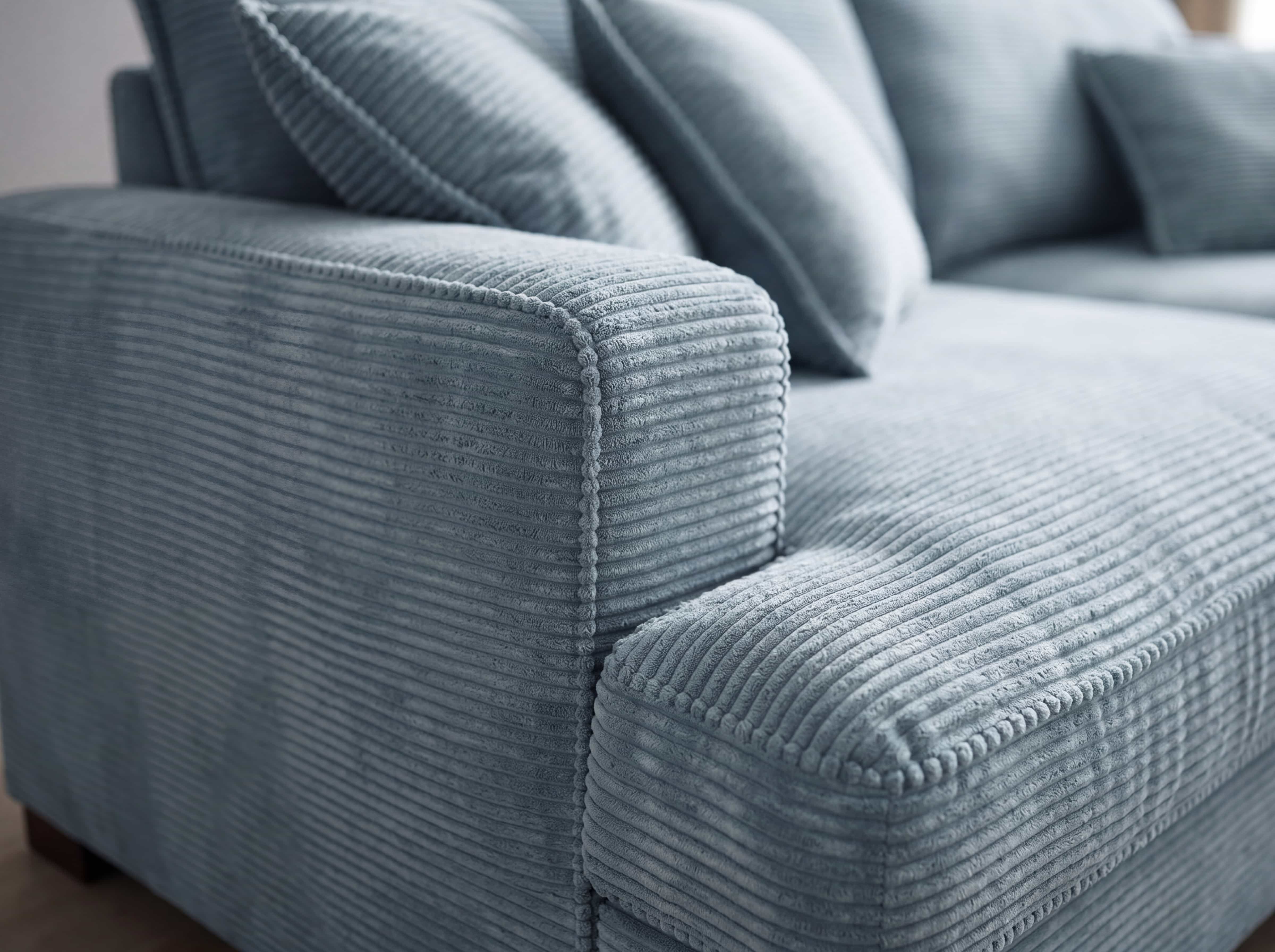 Ecksofa mit Armlehne aus blauem Cordstoff mit sichtbarer Rillenstruktur und passenden Kissen