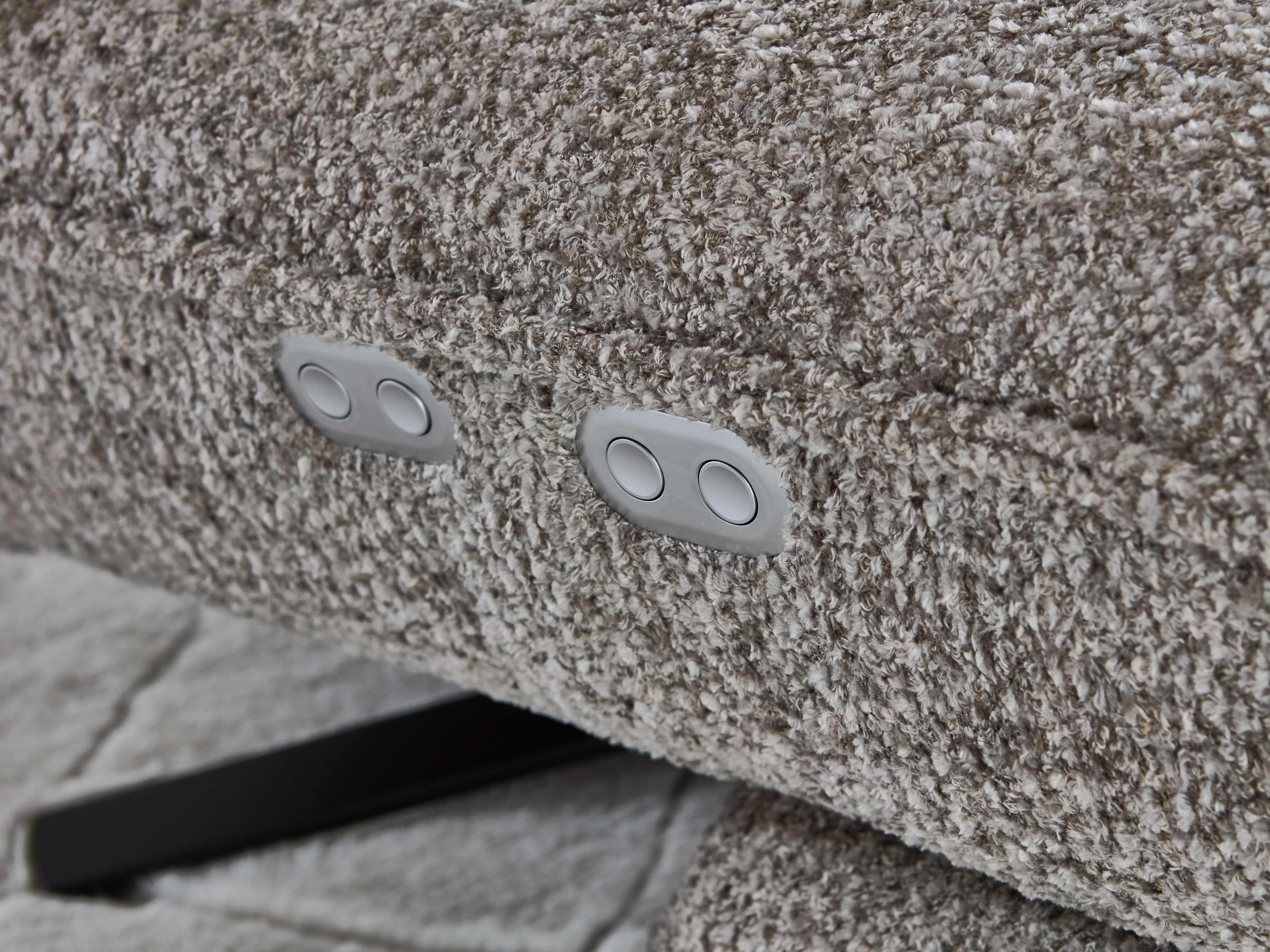 Detailaufnahme eines Sofas mit grauem, strukturiertem Stoffbezug und integrierten Bedienknöpfen