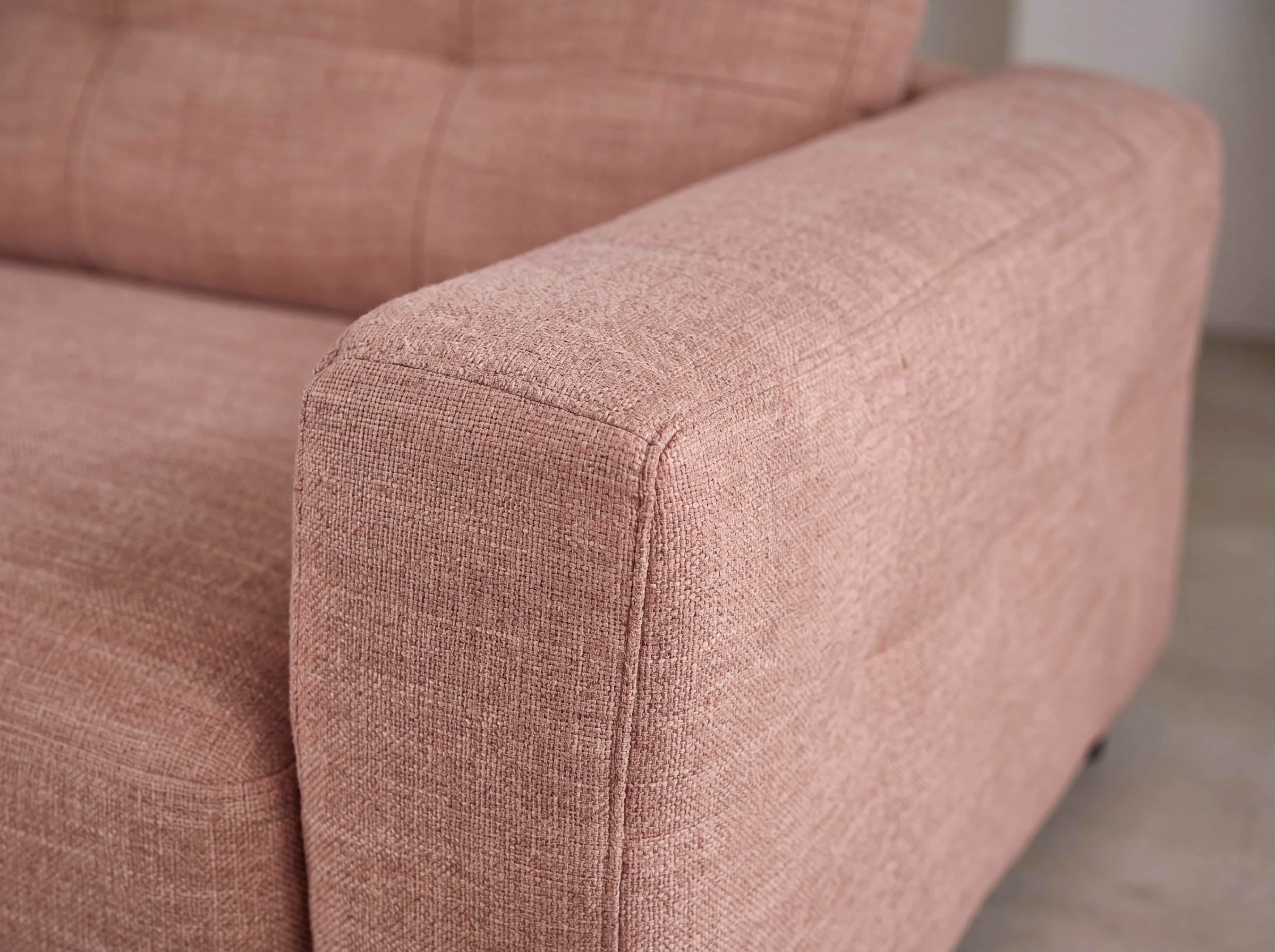 Ecksofa Modellname mit breiter Armlehne, rosa Stoffbezug und markanter Struktur in Nahaufnahme