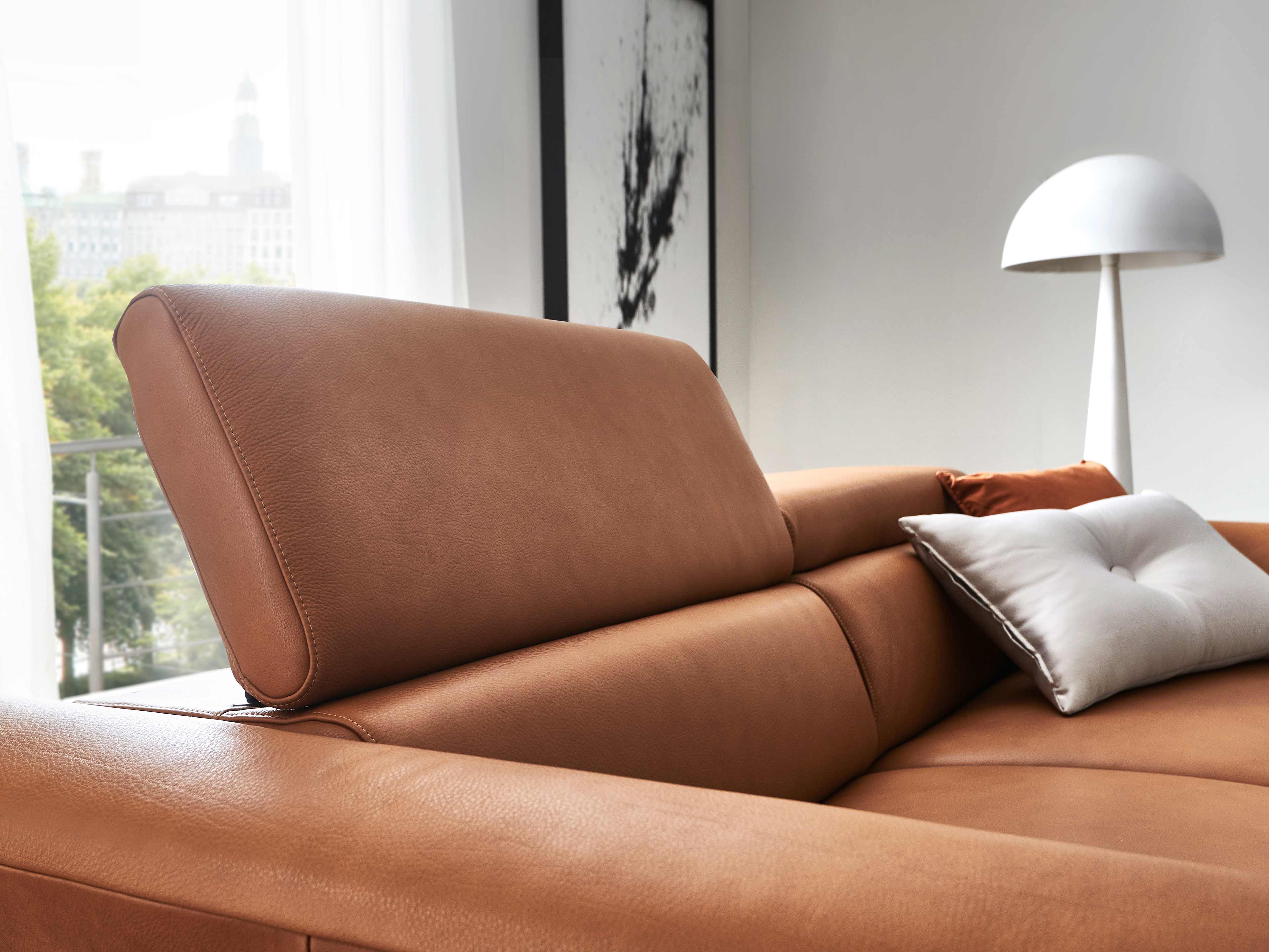 Ecksofa Kabs Leder braun mit verstellbarer Kopfstütze, Kissen und breiter Armlehne im Detail