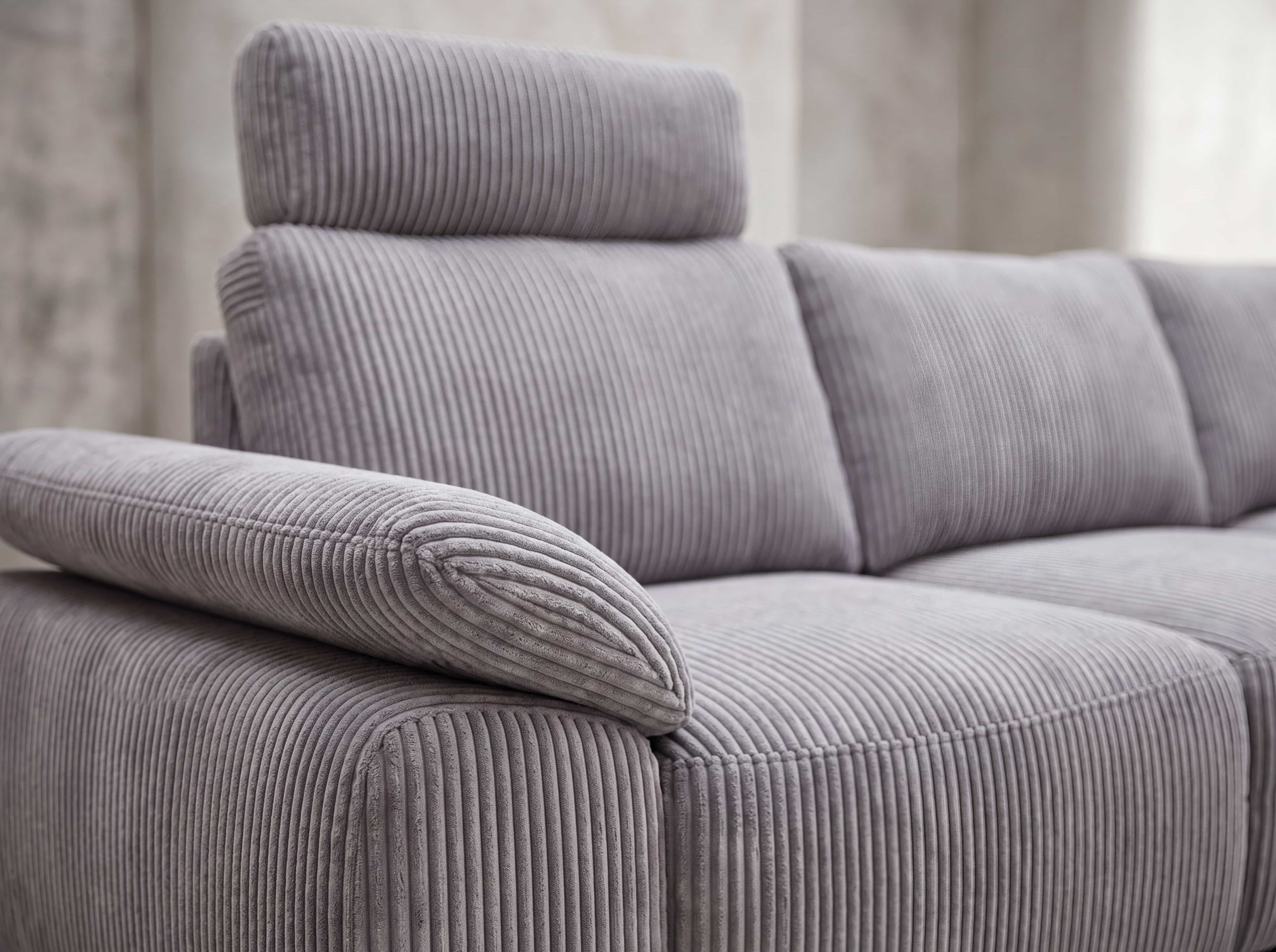 Ecksofa Kazar – Detailansicht des grauen Cordbezugs mit Armlehne, Rückenkissen und Kopfstütze