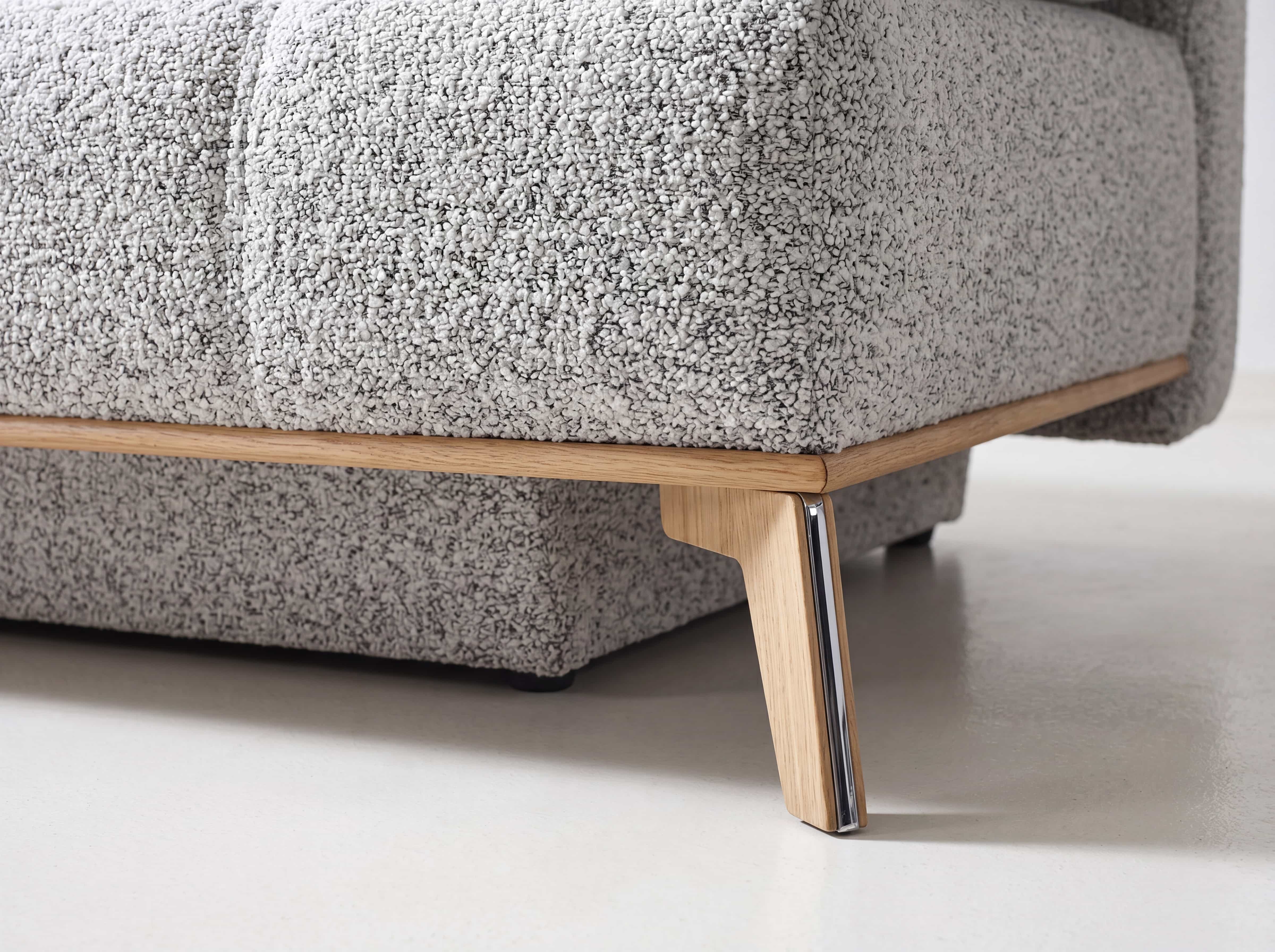 Sofa – Detailansicht des grauen Bouclébezugs mit hellem Holzgestell und Metallfuß