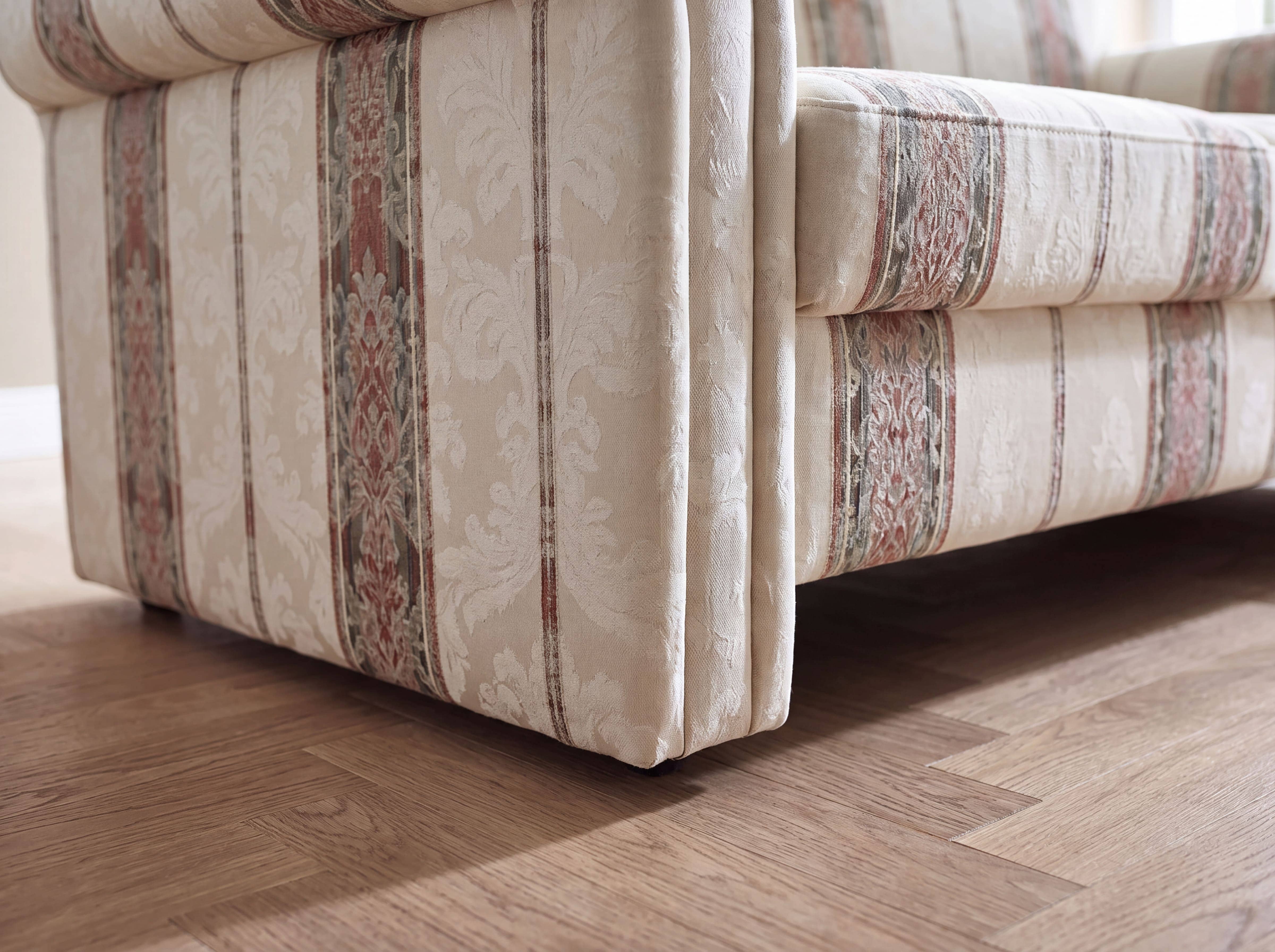 Sofa mit gemustertem Stoffbezug in Beige und Rot, gepolsterte Armlehne und Sitzfläche sichtbar