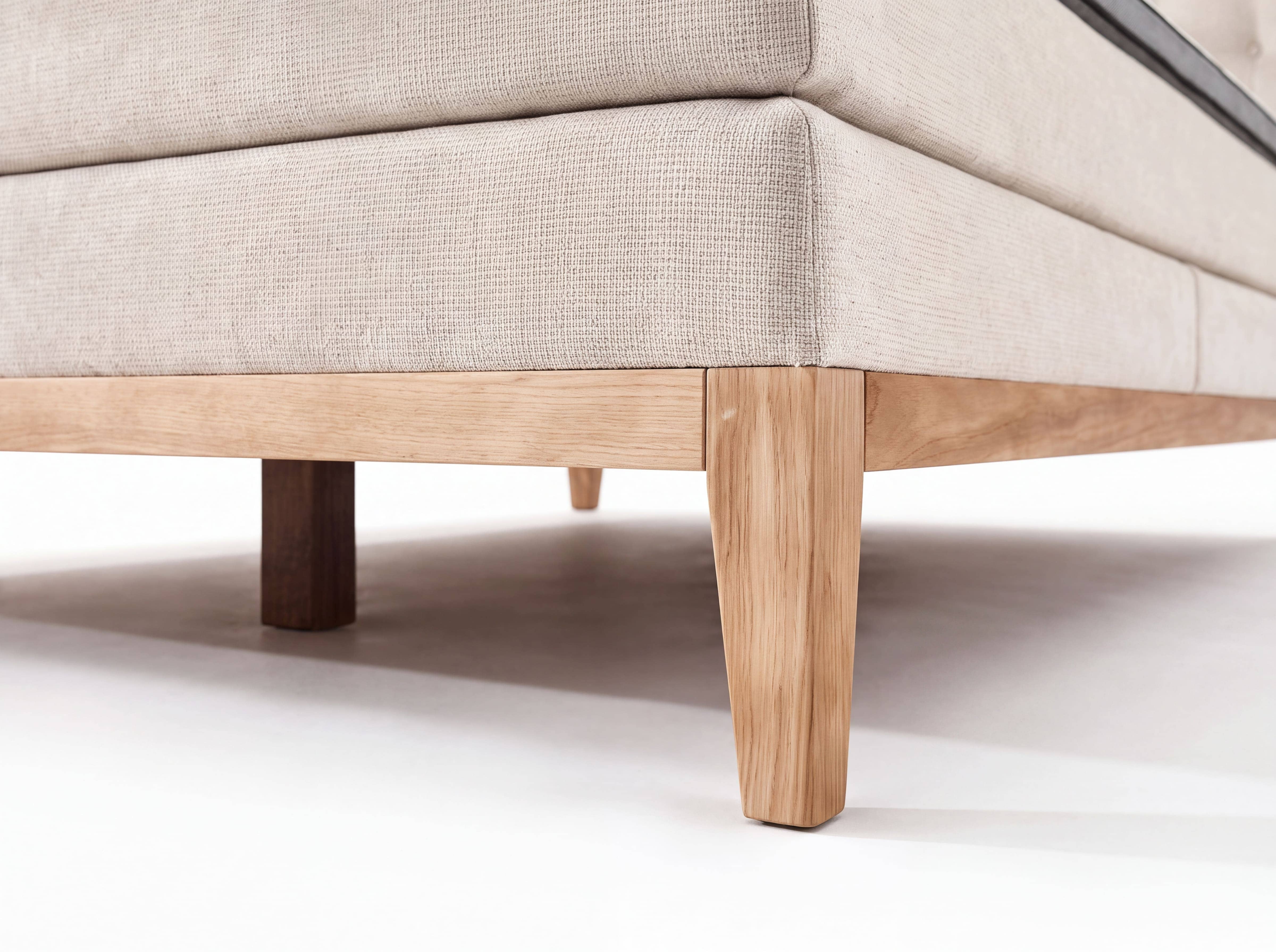 Boxspringbett mit beigefarbenem Stoffbezug und Massivholzrahmen, eckige Holzfüße sichtbar