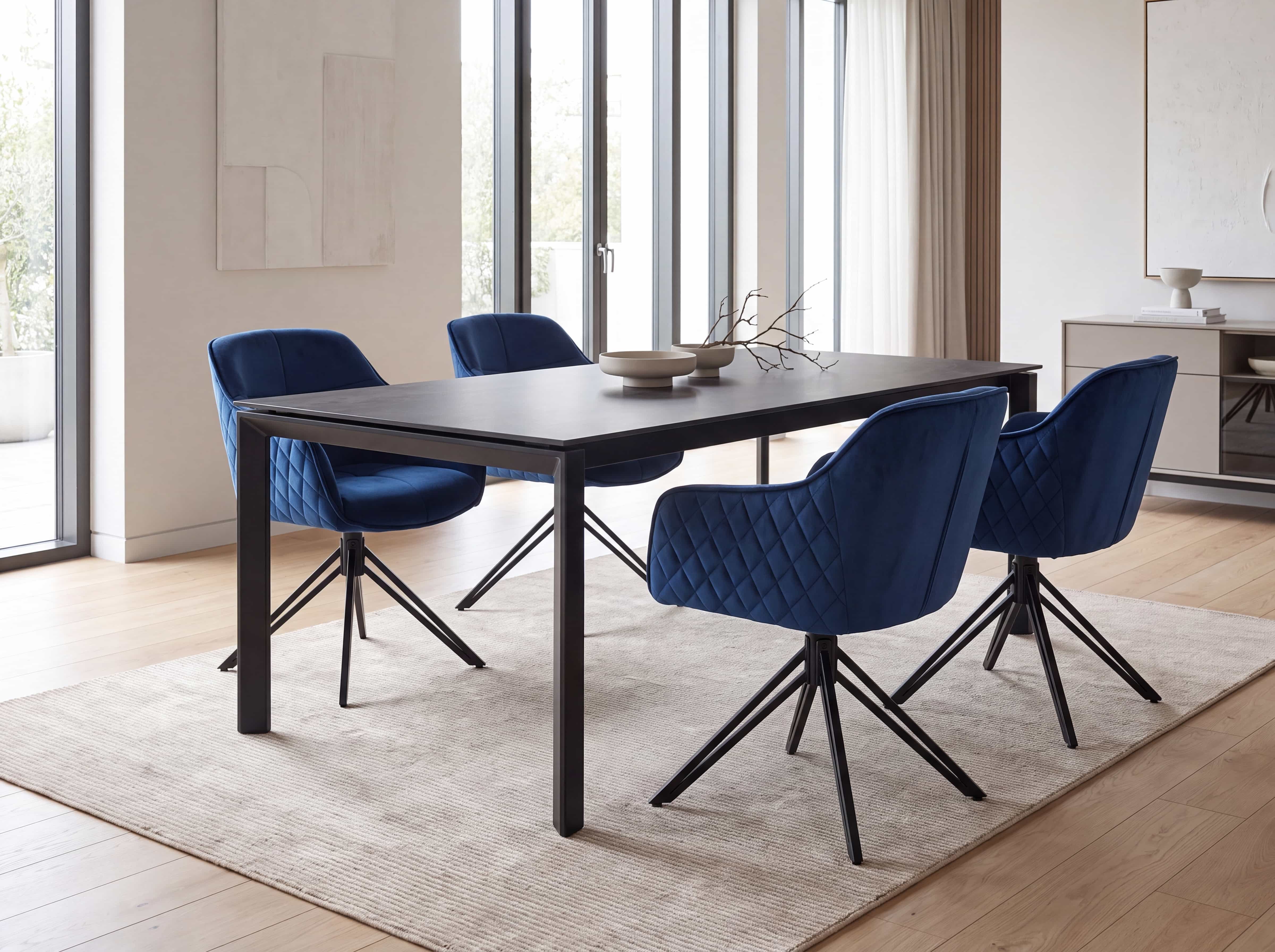 Vier Esszimmerstühle mit blauem Stoffbezug und Rautensteppung, Metallgestell, um einen schwarzen Tisch