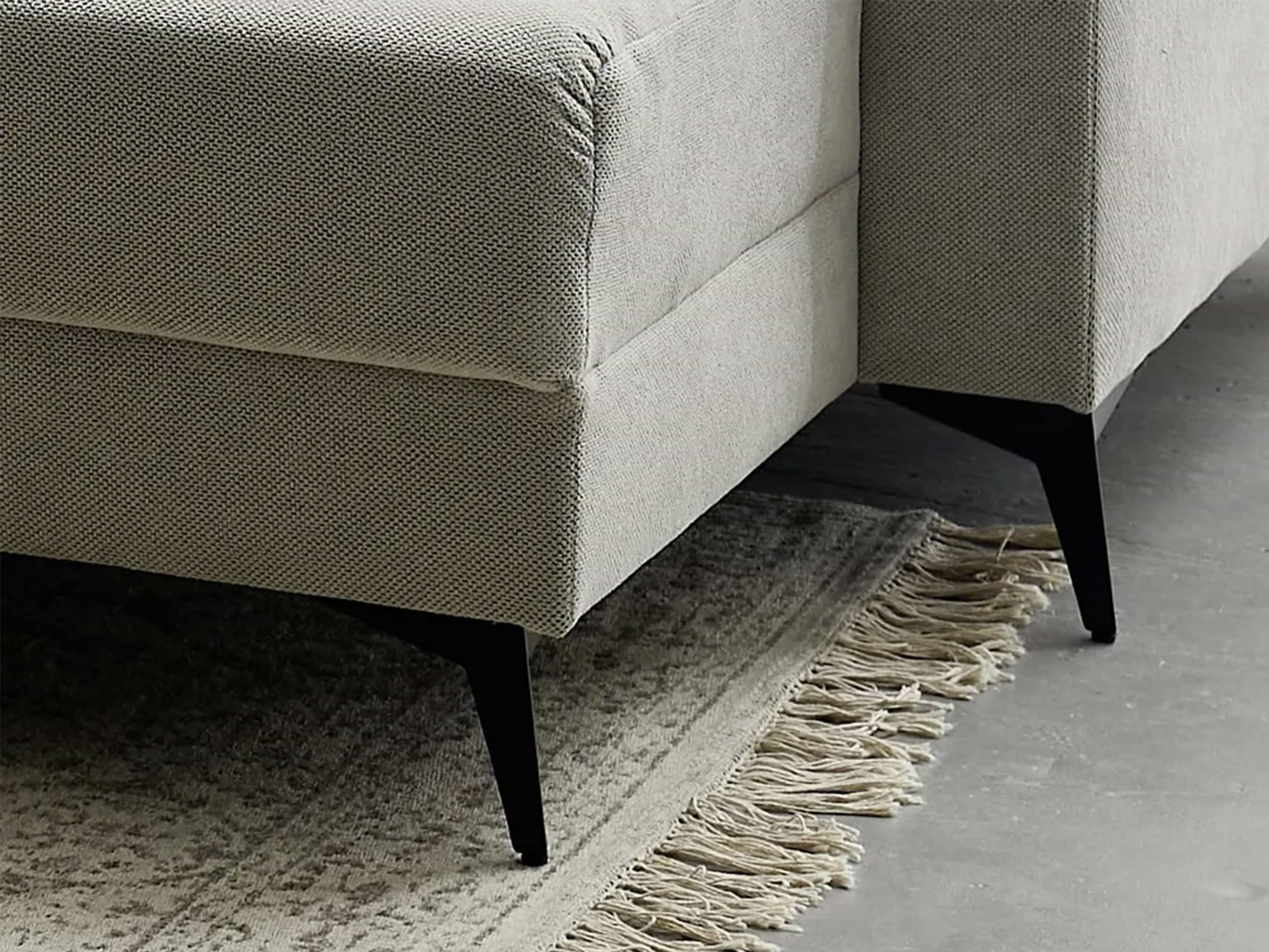 Ecksofa mit beigefarbenem Stoffbezug und schwarzen, nach außen gerichteten Metallfüßen