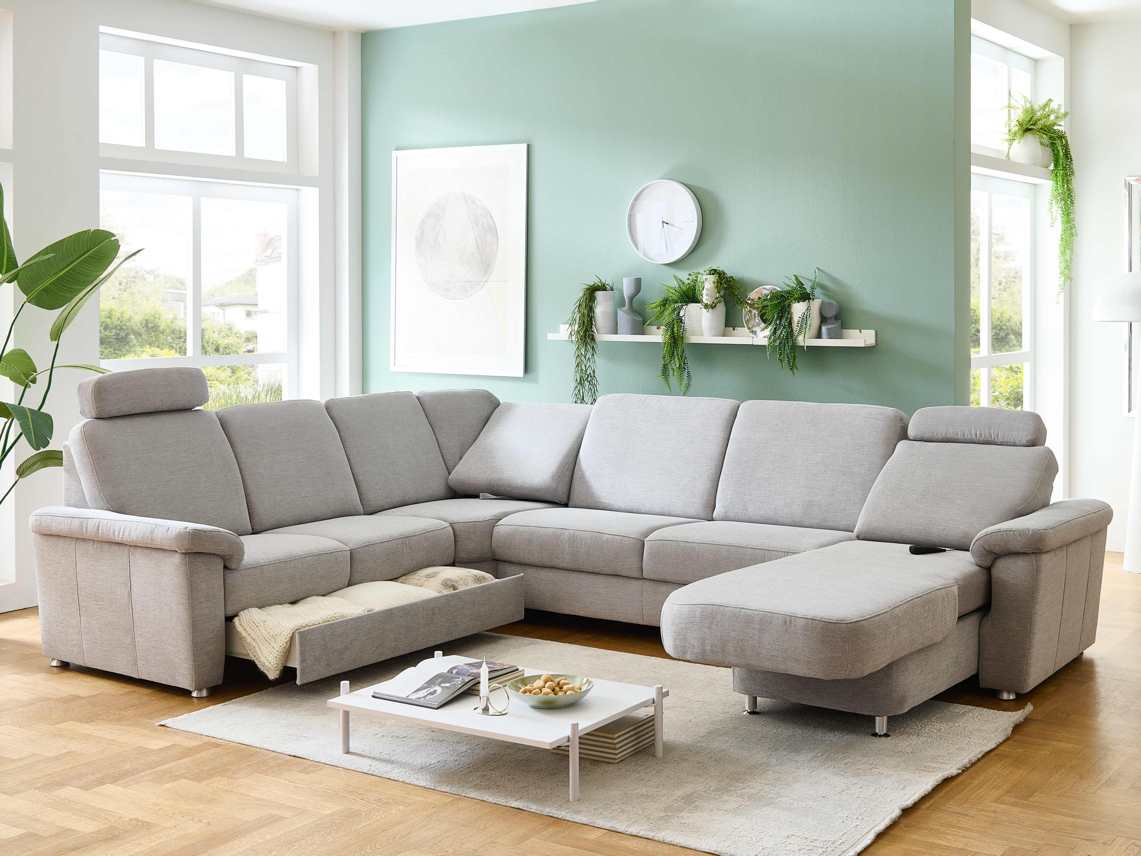 Ecksofa mit grauem Stoffbezug, verstellbaren Kopfstützen, Armlehnen und integriertem Bettkasten
