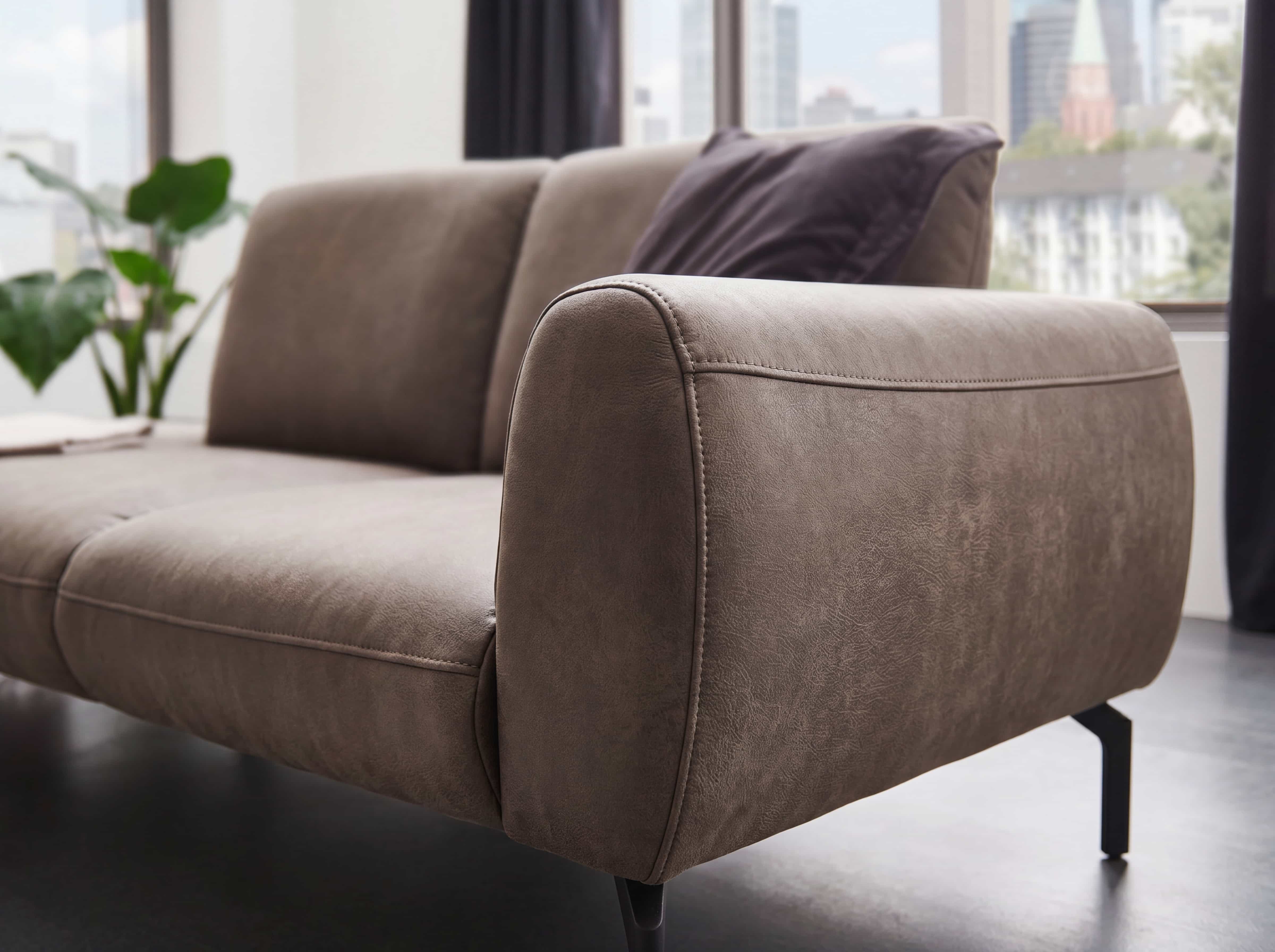 Ecksofa Temara mit braunem Stoffbezug, Armlehnen und schwarzen Metallfüßen in Nahaufnahme