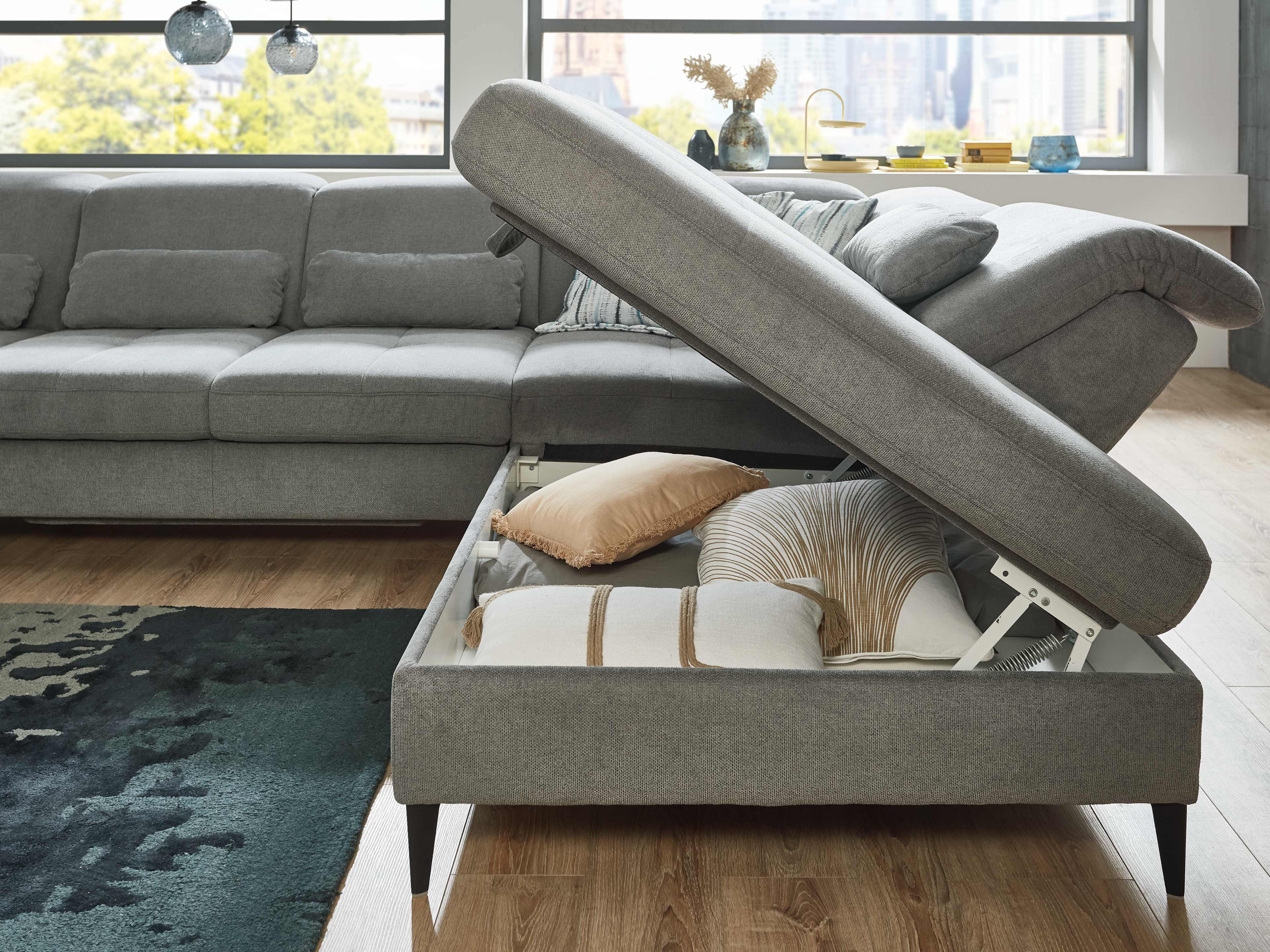 Ecksofa aus grauem Stoff mit Ottomane, aufklappbarem Stauraum und schwarzen Füßen
