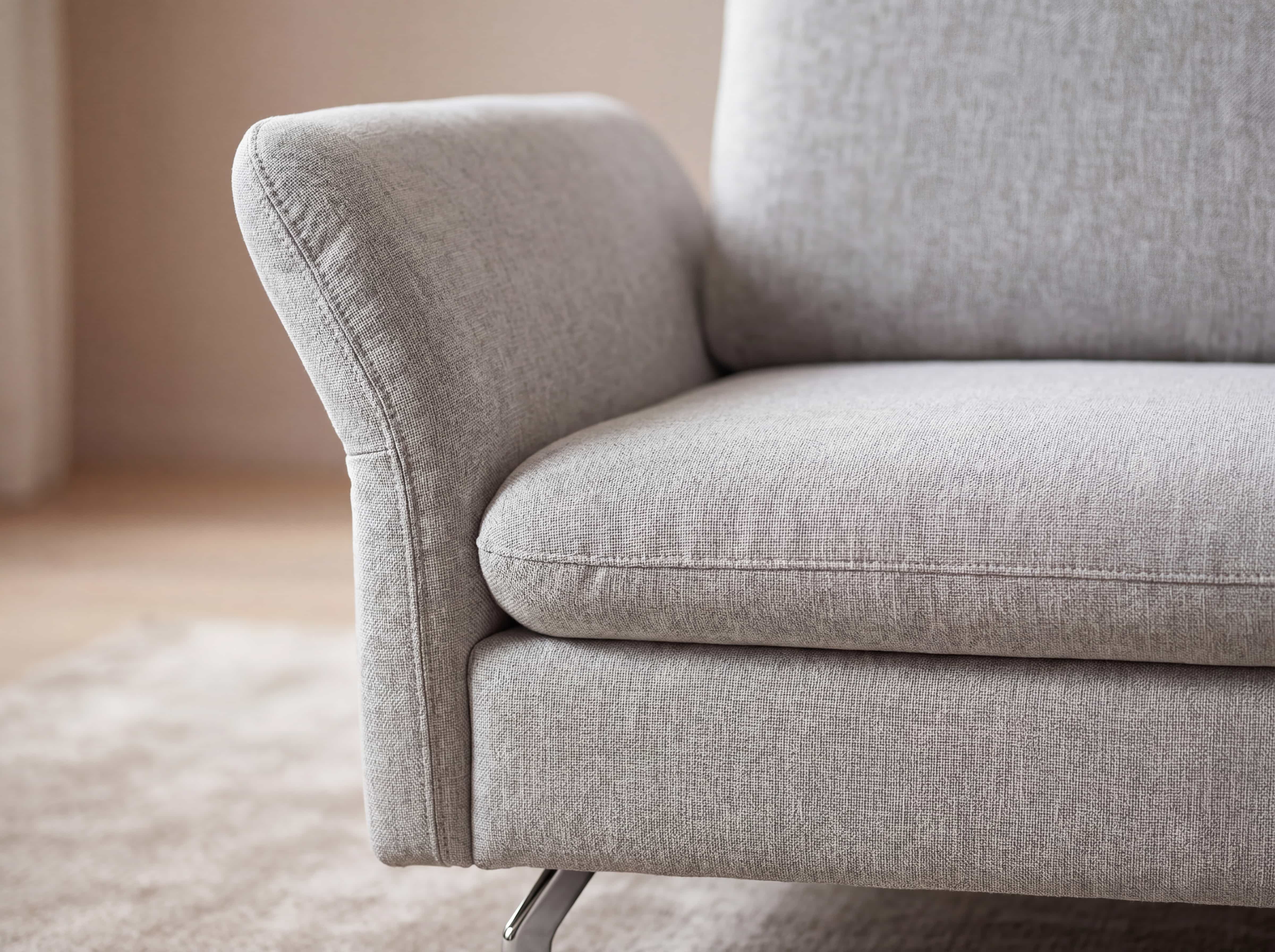 Ecksofa im Detail mit hellgrauem Stoffbezug, gepolsterter Rückenlehne und Armlehne, Metallfuß