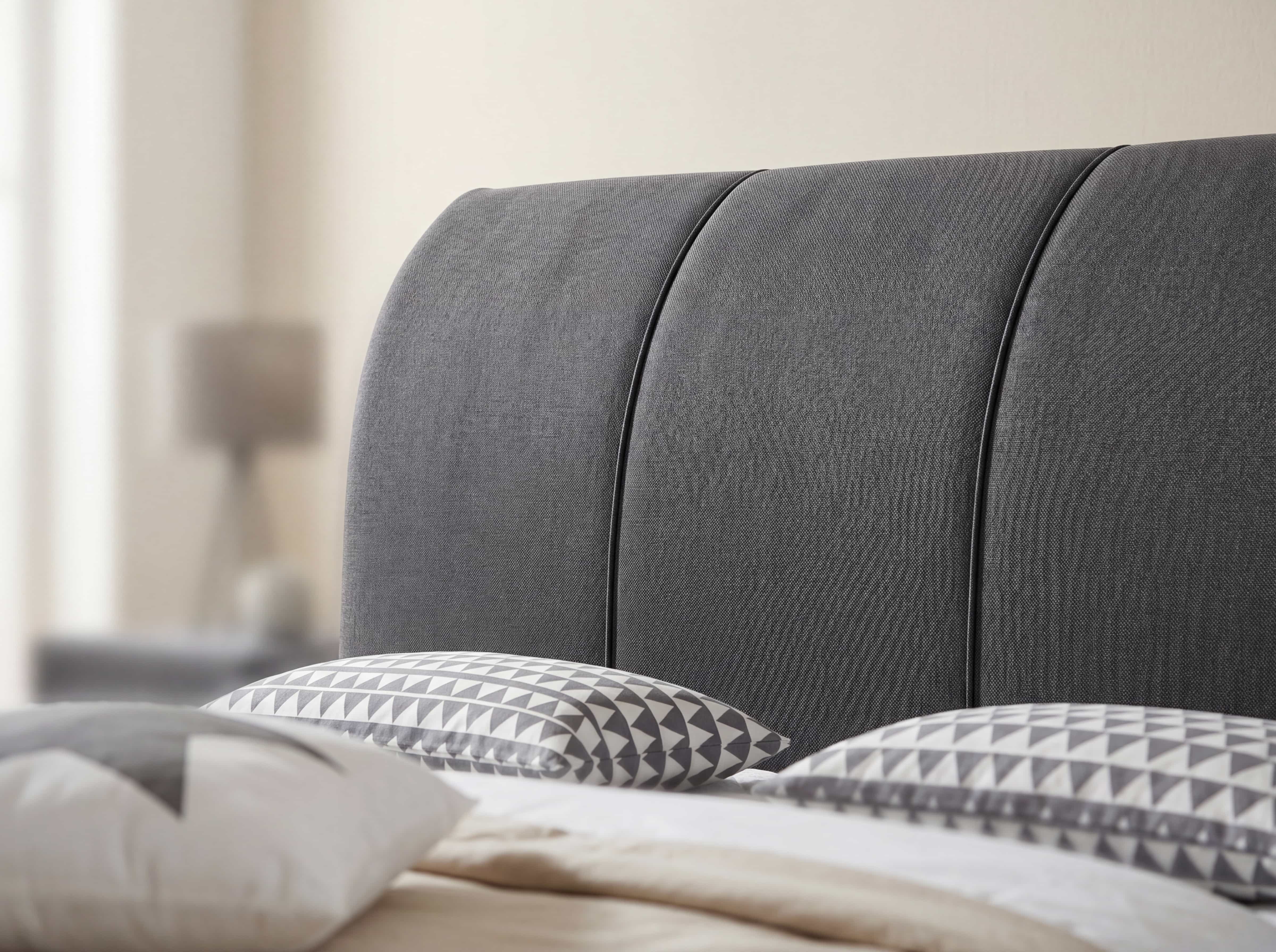 Boxspringbett mit grauem, strukturiertem Stoffkopfteil in drei Segmenten, gepolstert
