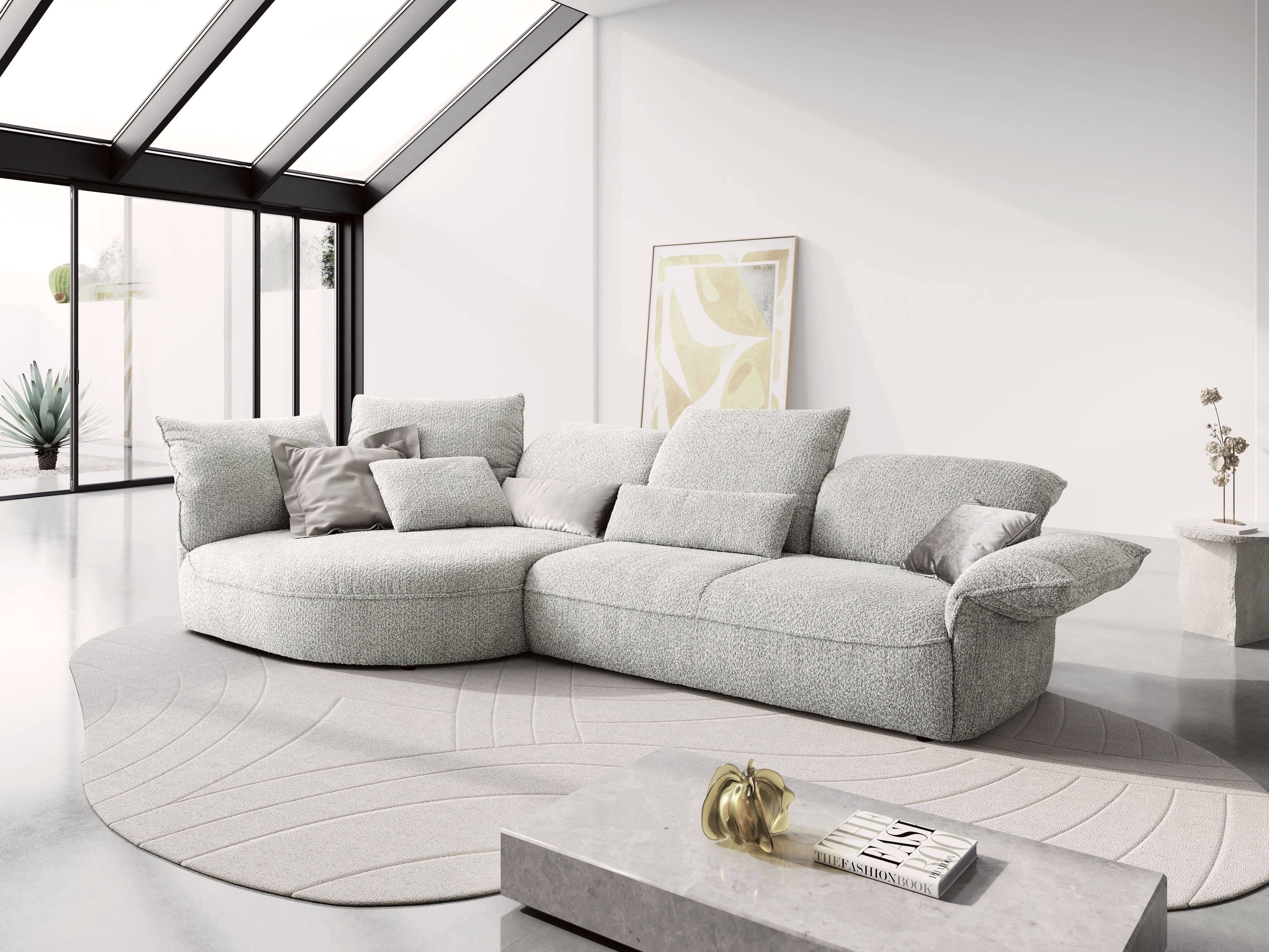 Ecksofa Modell mit hellgrauem Stoffbezug, gepolsterten Armlehnen und mehreren Kissen