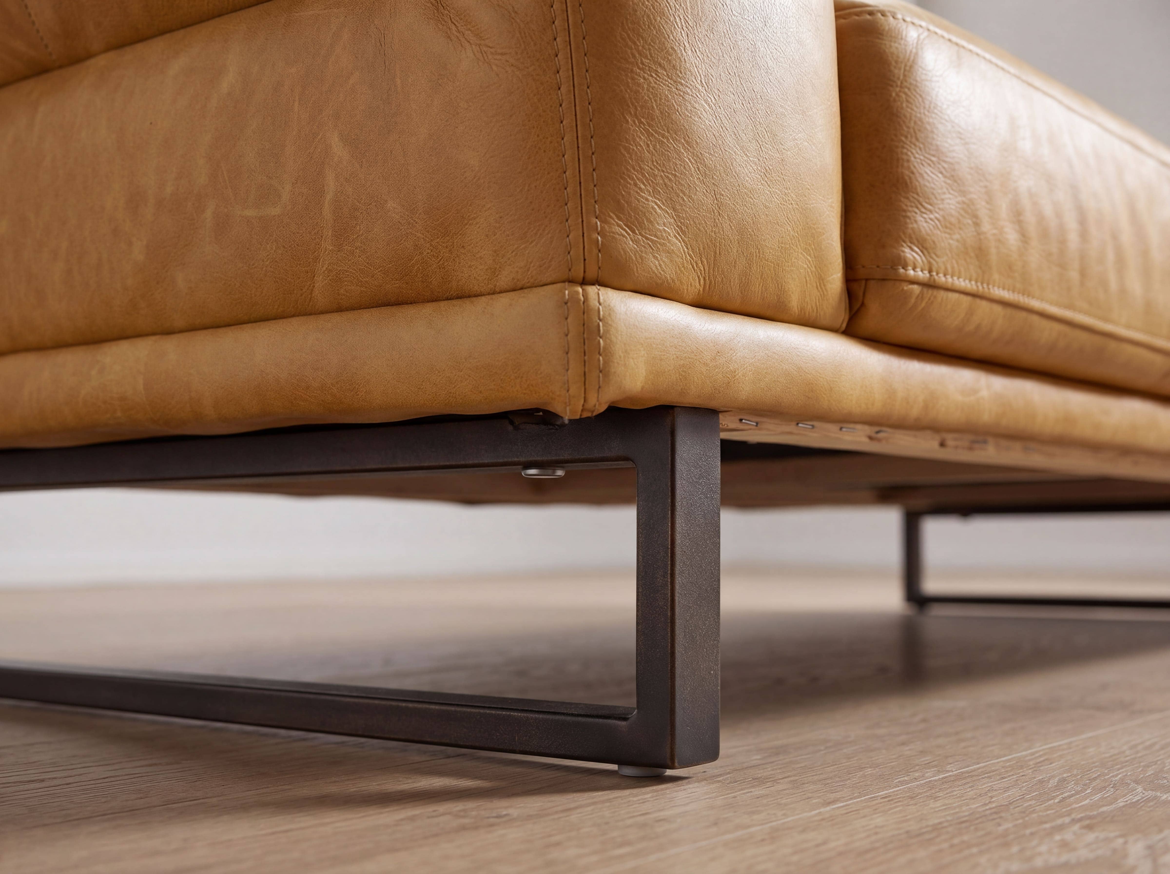Ecksofa mit cognacfarbenem Lederbezug und schwarzem, eckigem Metallgestell in Nahaufnahme