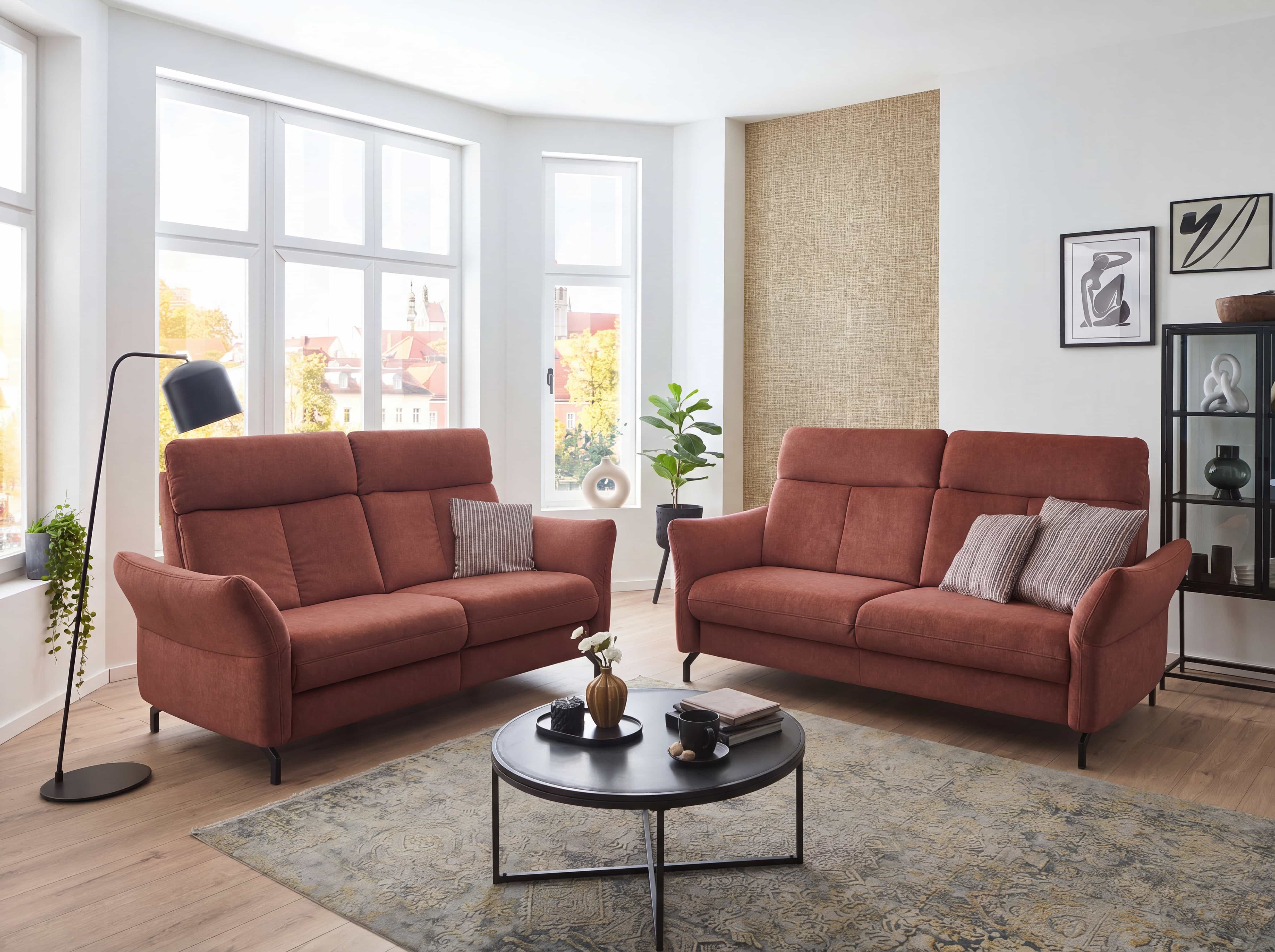 Zwei Sofas mit Stoffbezug in terrakotta, je zwei Sitzplätze, hohe Rückenlehnen, schmale Armlehnen.