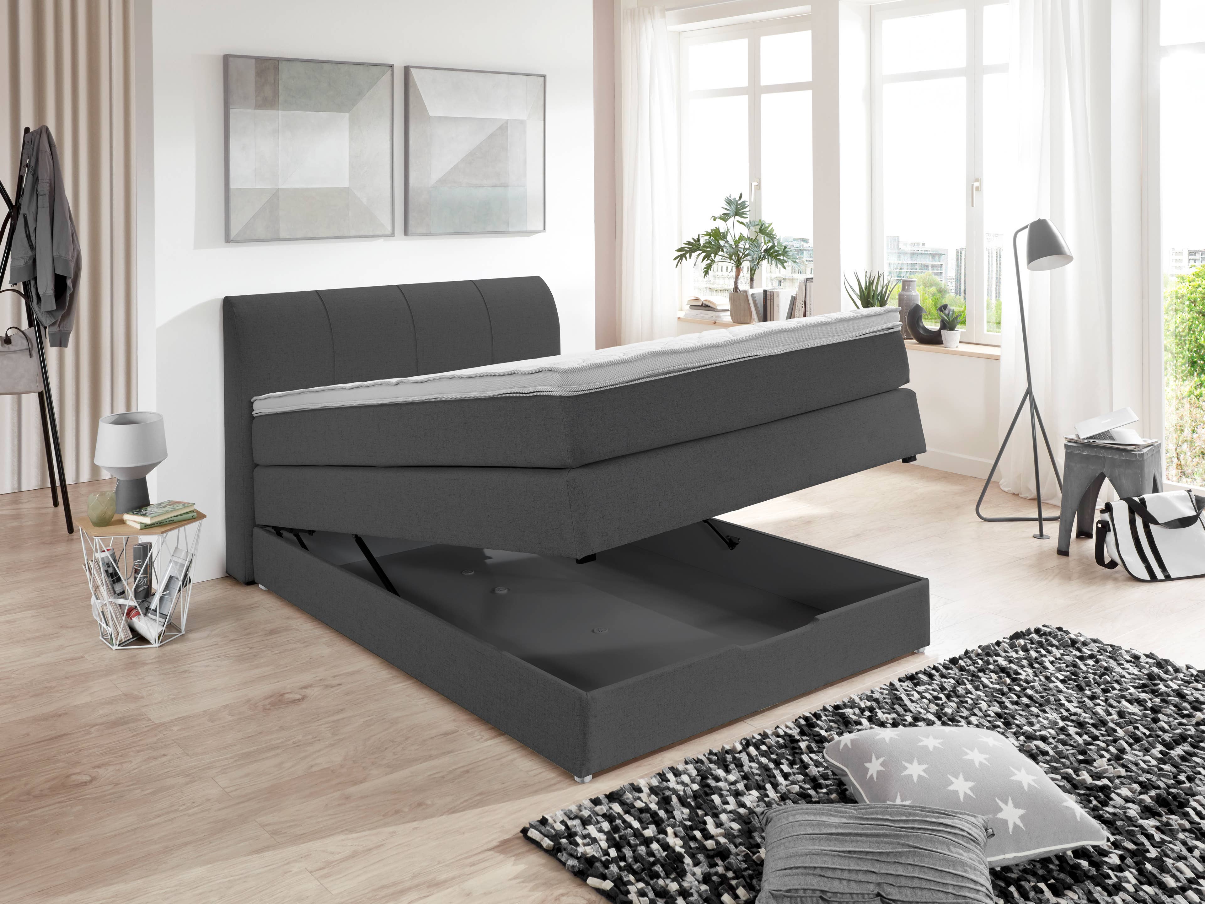 Boxspringbett in Dunkelgrau mit gepolstertem Kopfteil und aufklappbarer Liegefläche zur Stauraumnutzung