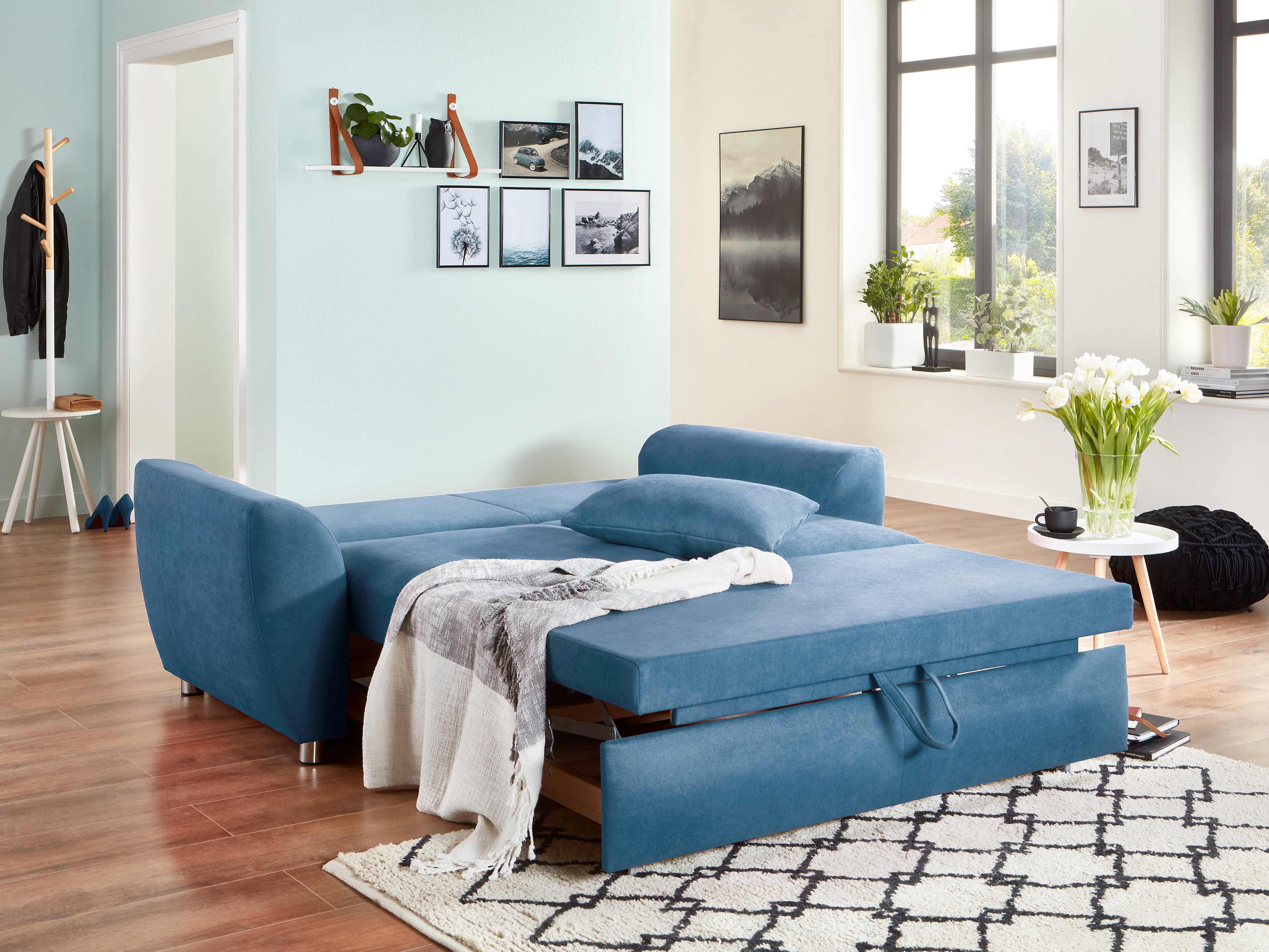 Ecksofa in Blau mit Stoffbezug, ausgezogen zur Schlaffunktion, abgerundete Armlehnen, chromfarbene Füße