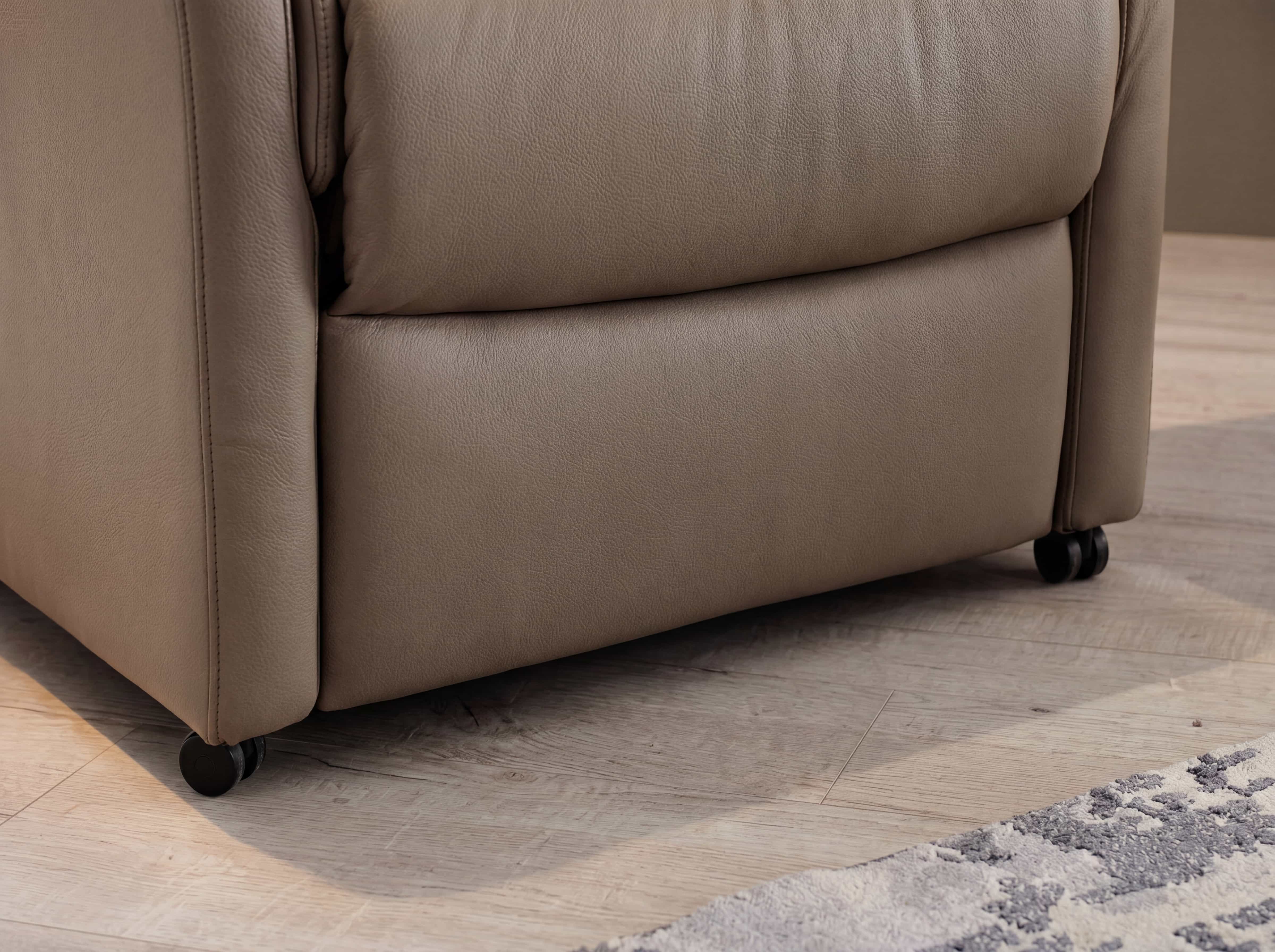 Relaxsessel Kuens – Detailansicht des braunen Bezugs mit sichtbaren schwarzen Rollen am Boden