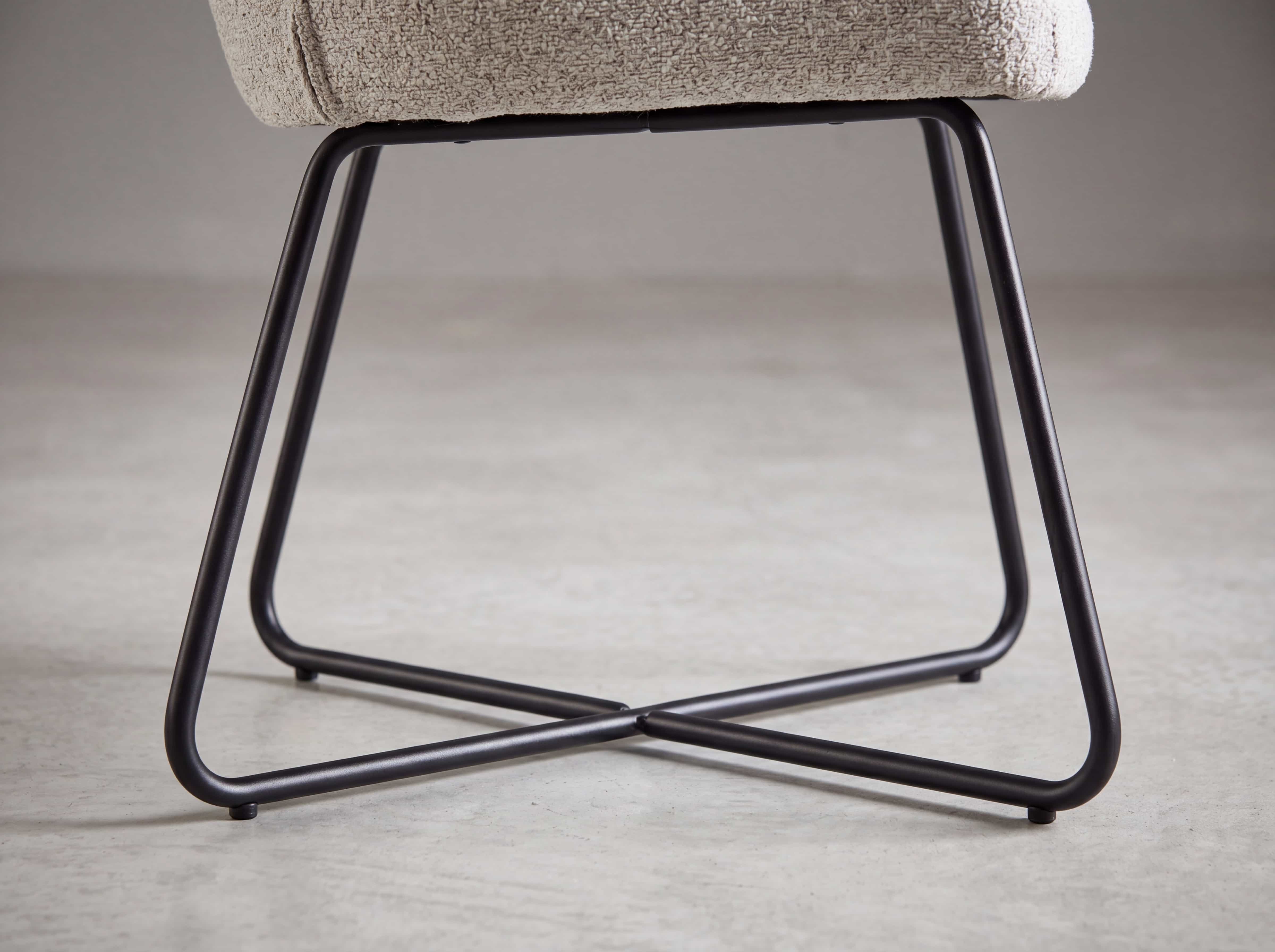 Esszimmerstuhl mit hell gepolsterter Sitzfläche und schwarzem Metallgestell mit Kreuzform.