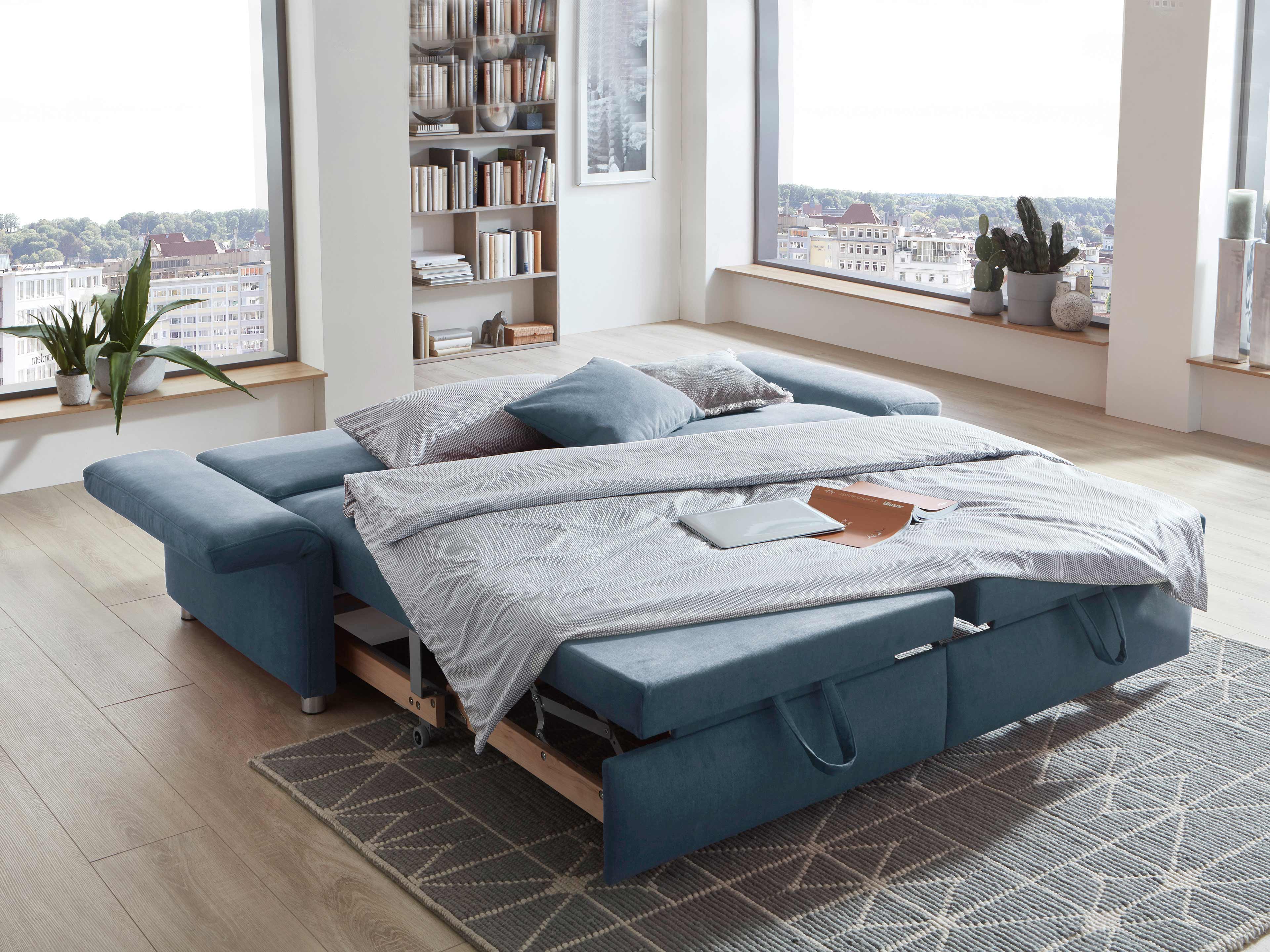 Schlafsofa mit Armlehnen in L-Form, Bezug aus blauem Stoff, ausgezogen mit Stauraum und Kissen