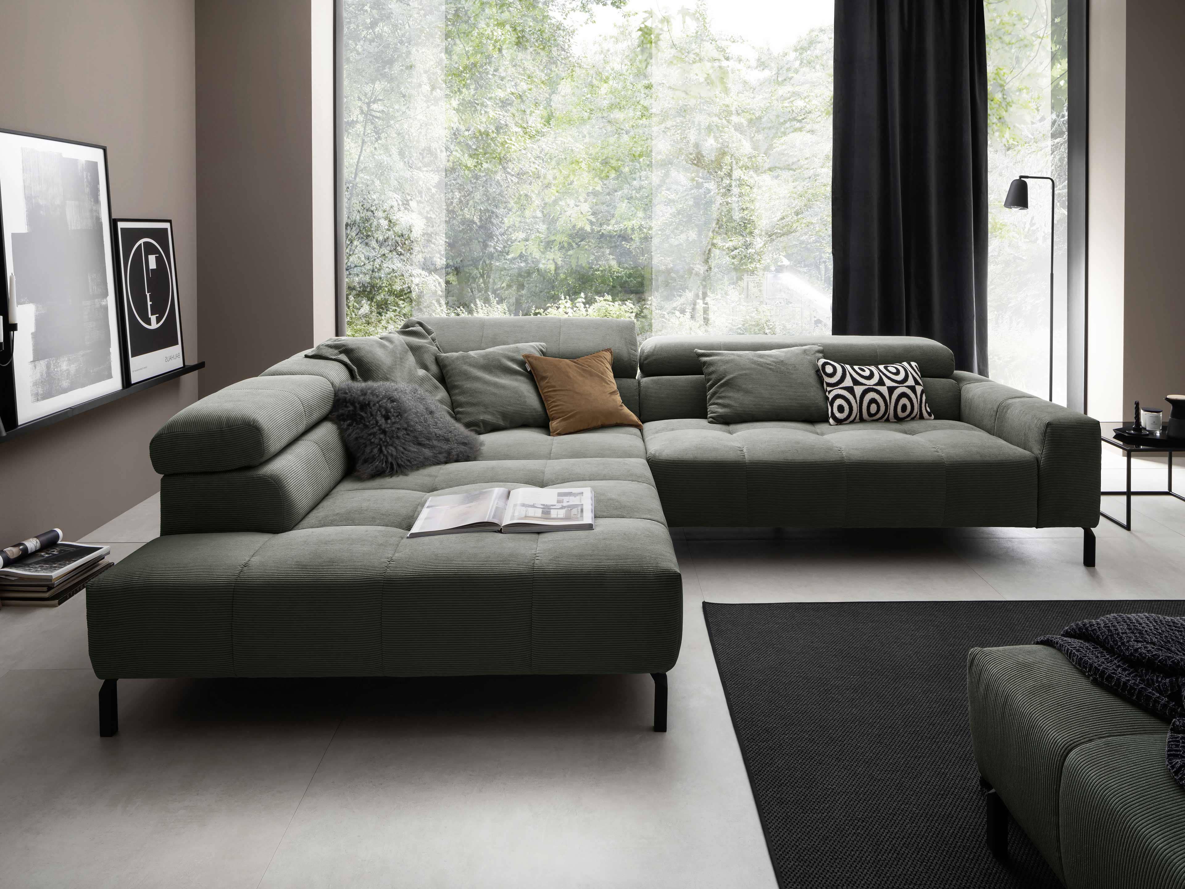 Ecksofa in L-Form mit grünem Cordbezug, breiten Armlehnen und schwarzen Metallfüßen