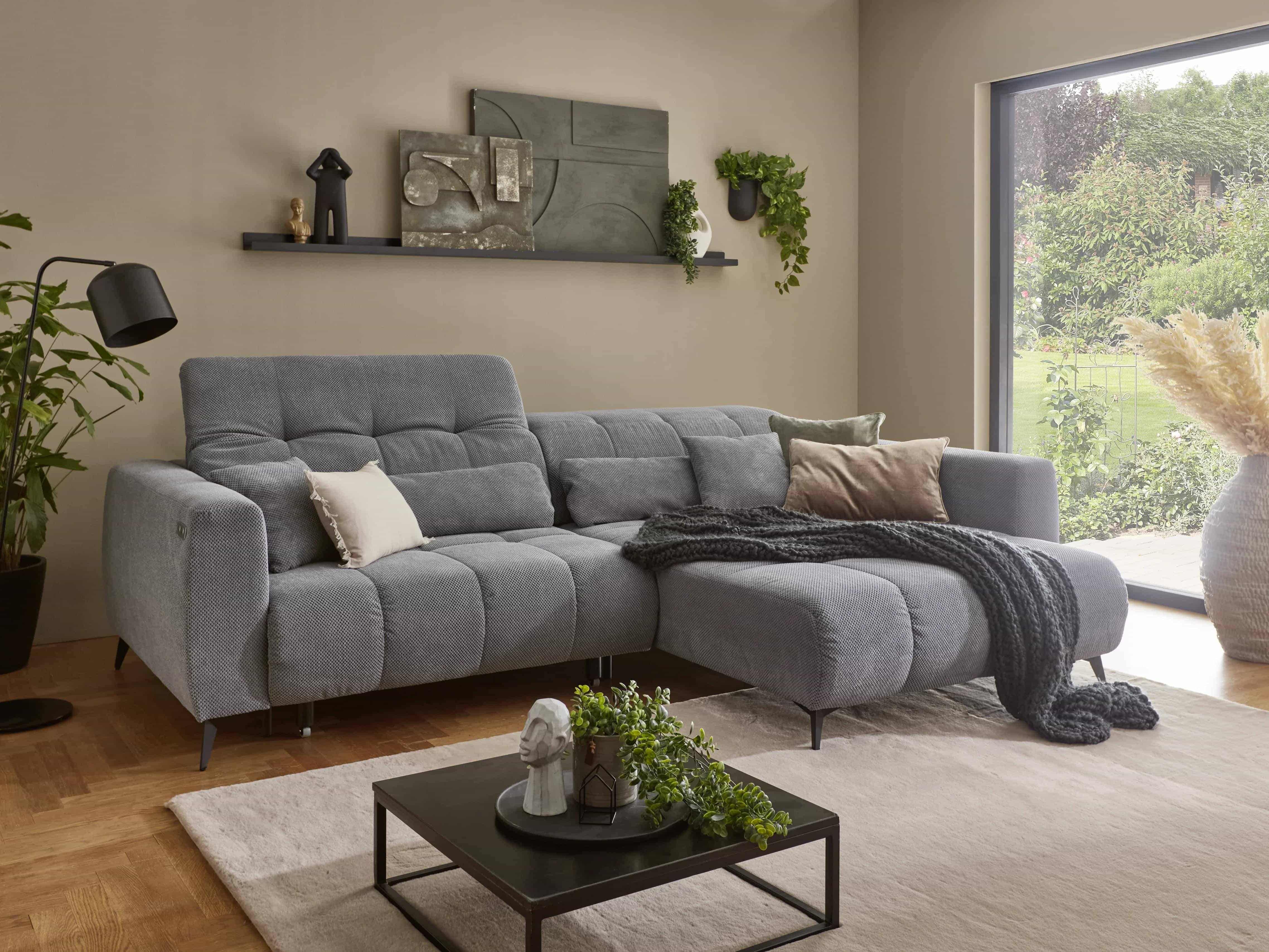 Ecksofa mit hellgrauem Stoffbezug, breiten Armlehnen, gepolsterter Sitzfläche und Metallfüßen