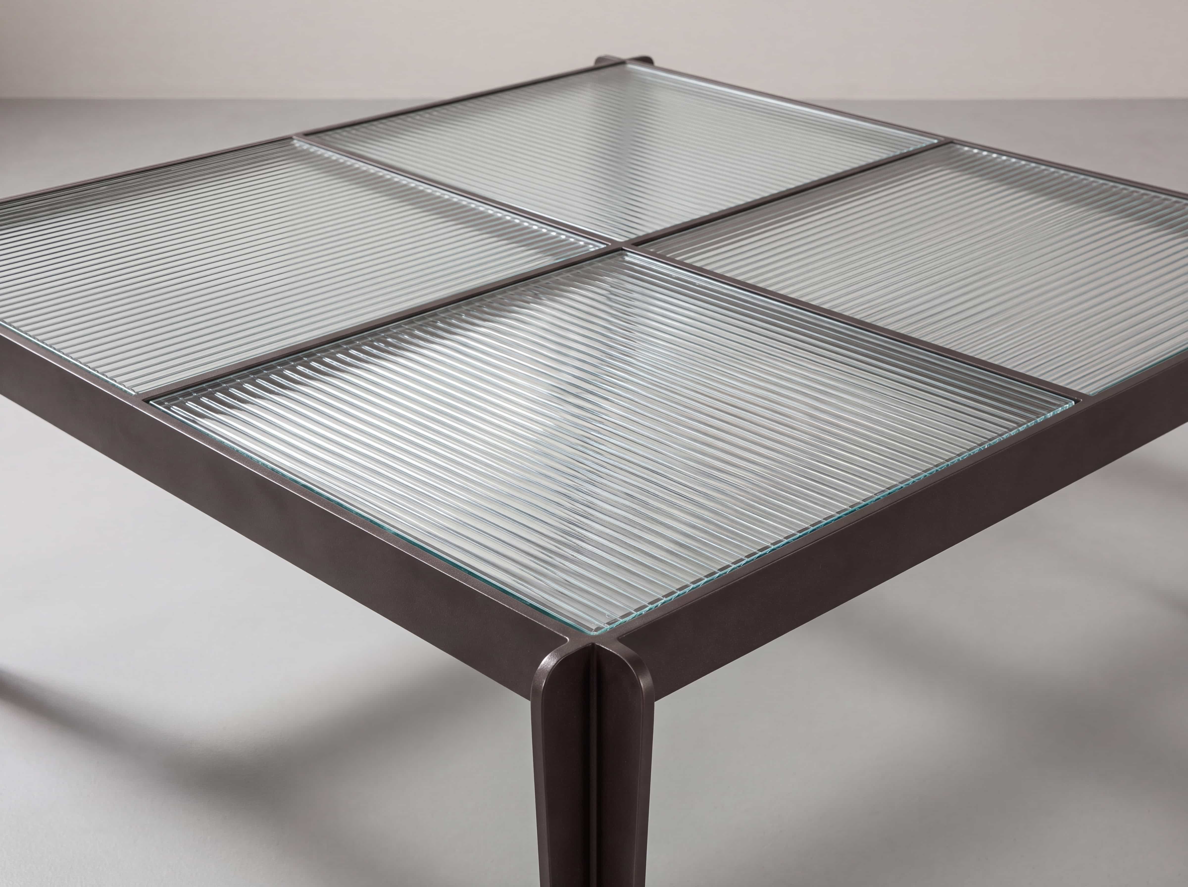 Couchtisch mit quadratischer, geriffelter Glasplatte und dunklem Metallgestell in moderner Ausführung