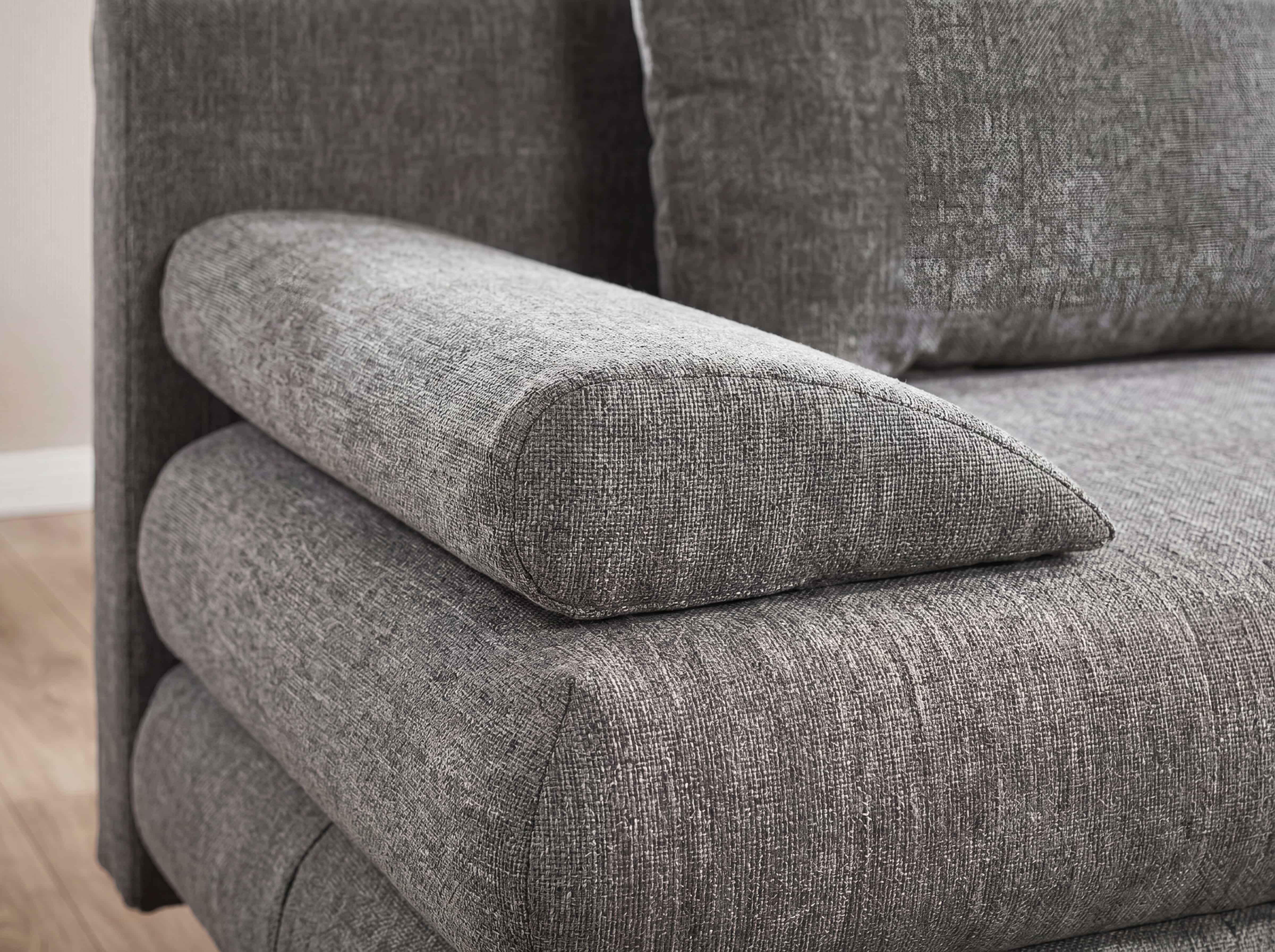 Ecksofa Kabs mit grauem Stoffbezug, breiter gepolsterter Armlehne und strukturierter Oberfläche