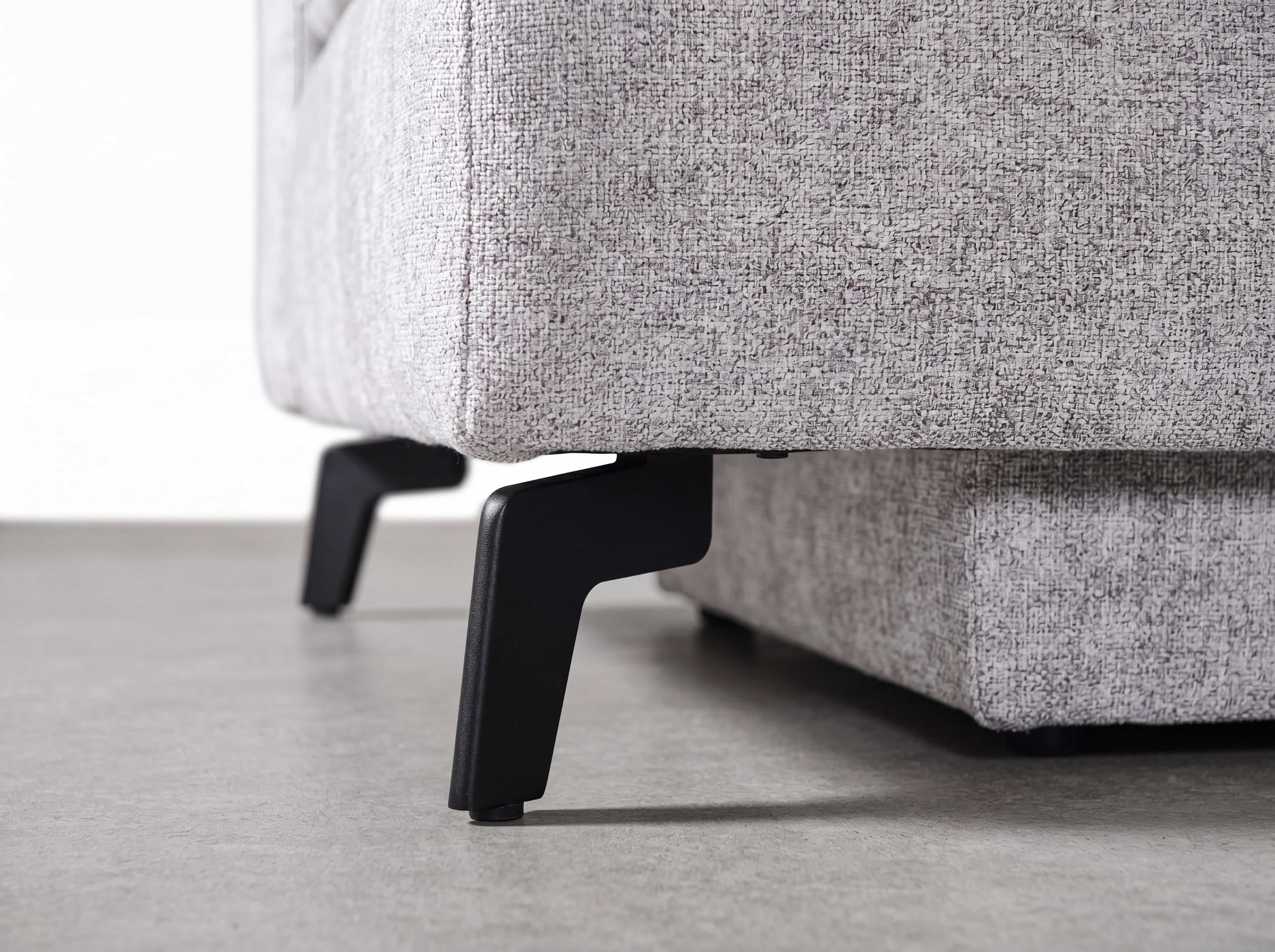Boxspringbett mit hellgrauem Stoffbezug und schwarzen Metallfüßen in Nahaufnahme, modernes Design