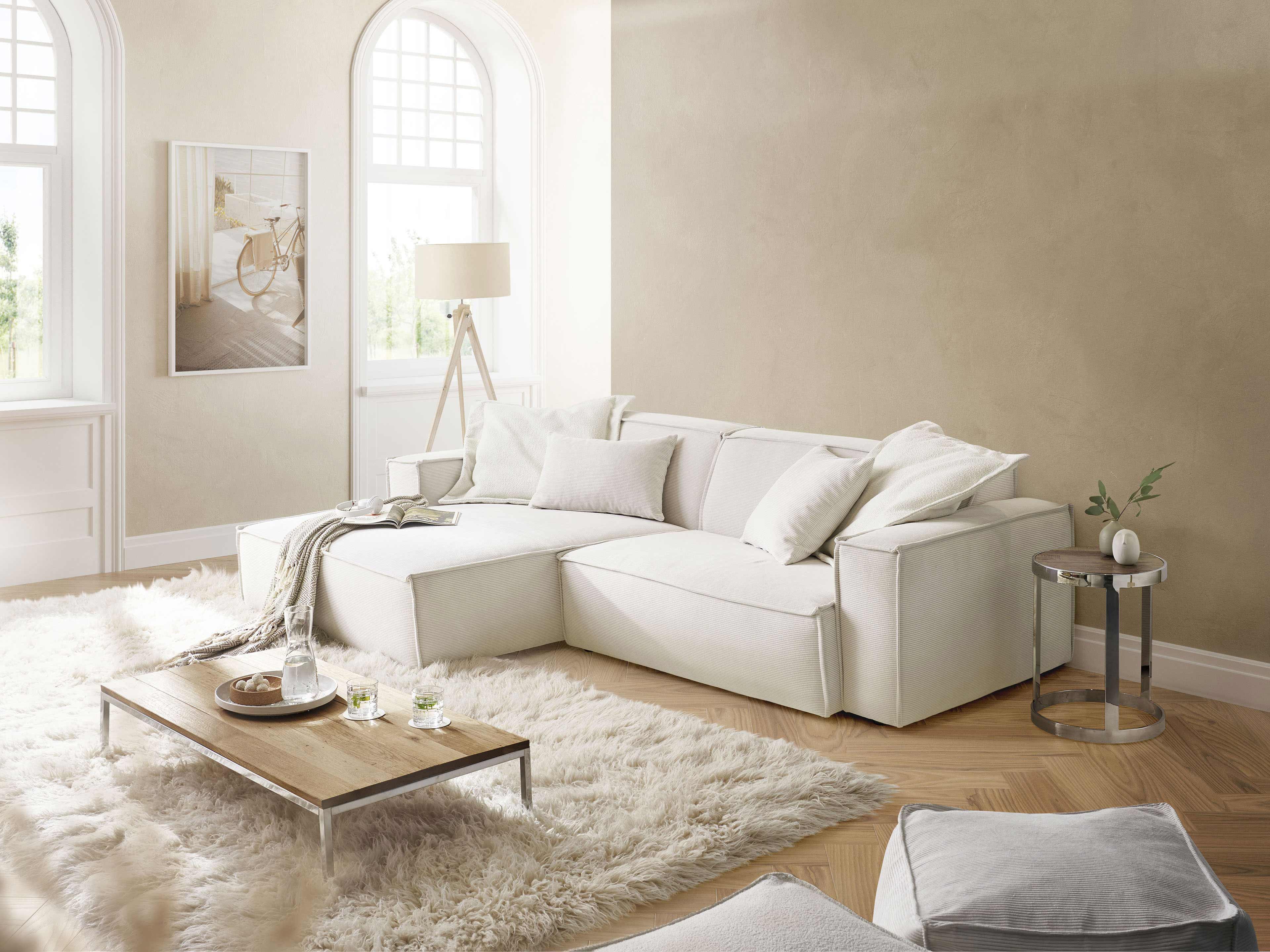 Ecksofa Kabs Polsterwelt mit hellen Stoffbezug, klaren Linien, breiten Armlehnen und losen Kissen