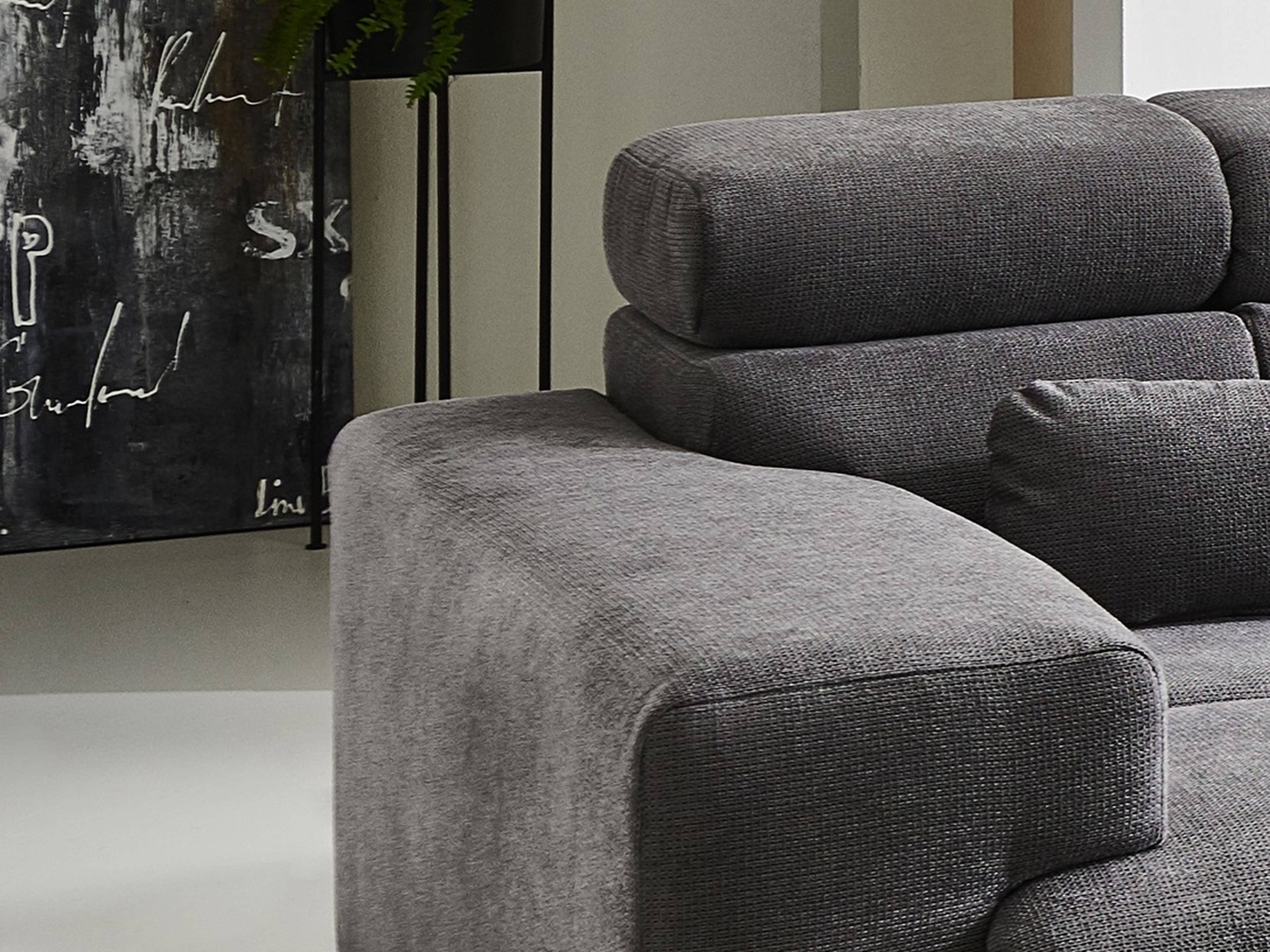 Ecksofa Modell mit grauem Stoffbezug, breiten Armlehnen und gepolsterten verstellbaren Kopfstützen