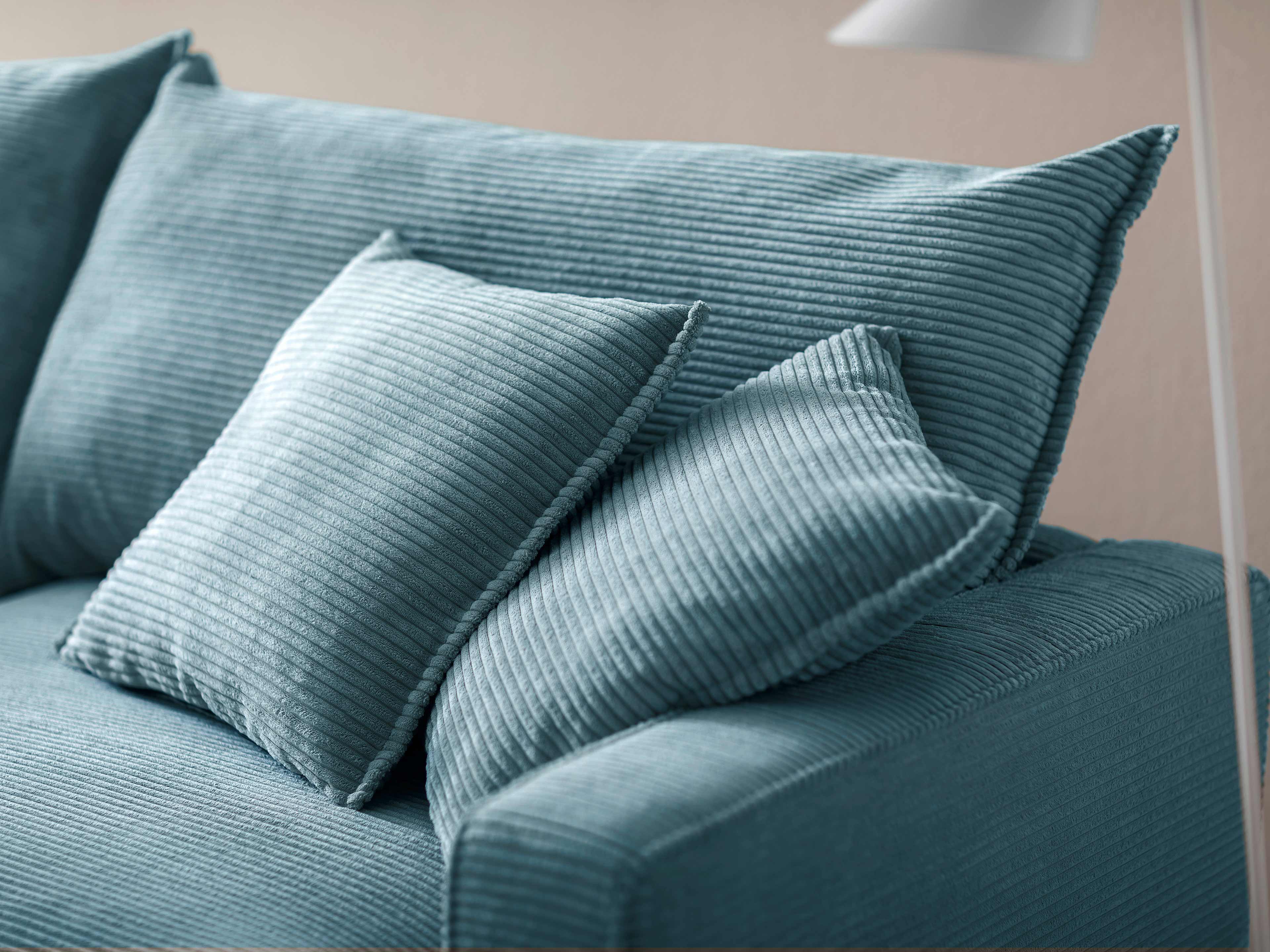 Ecksofa mit geripptem Stoffbezug in Hellblau und breiten Rücken- und Zierkissen