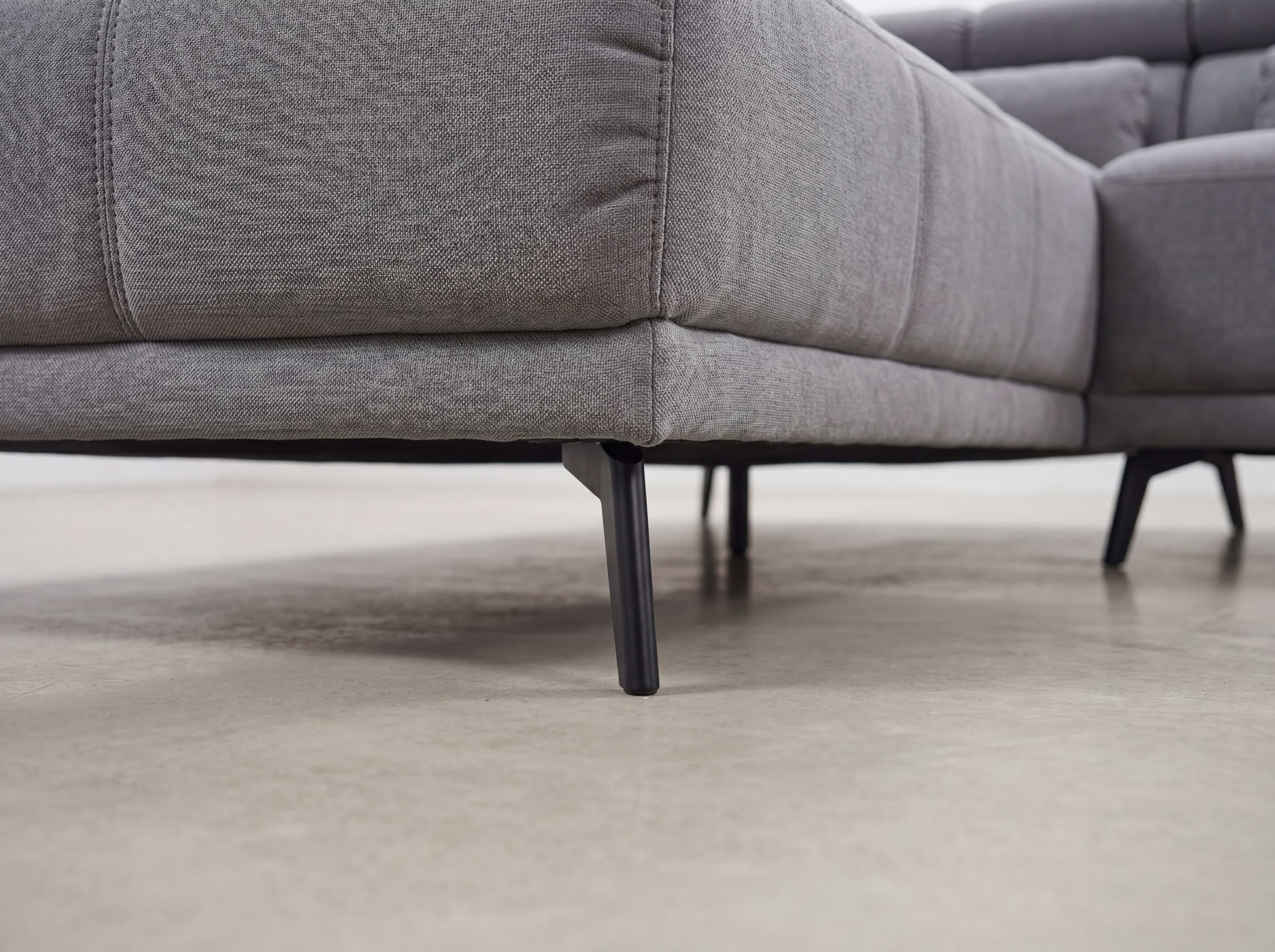 Ecksofa mit grauem Stoffbezug und schwarzen Metallfüßen, gepolsterte Sitzfläche, Nahaufnahme