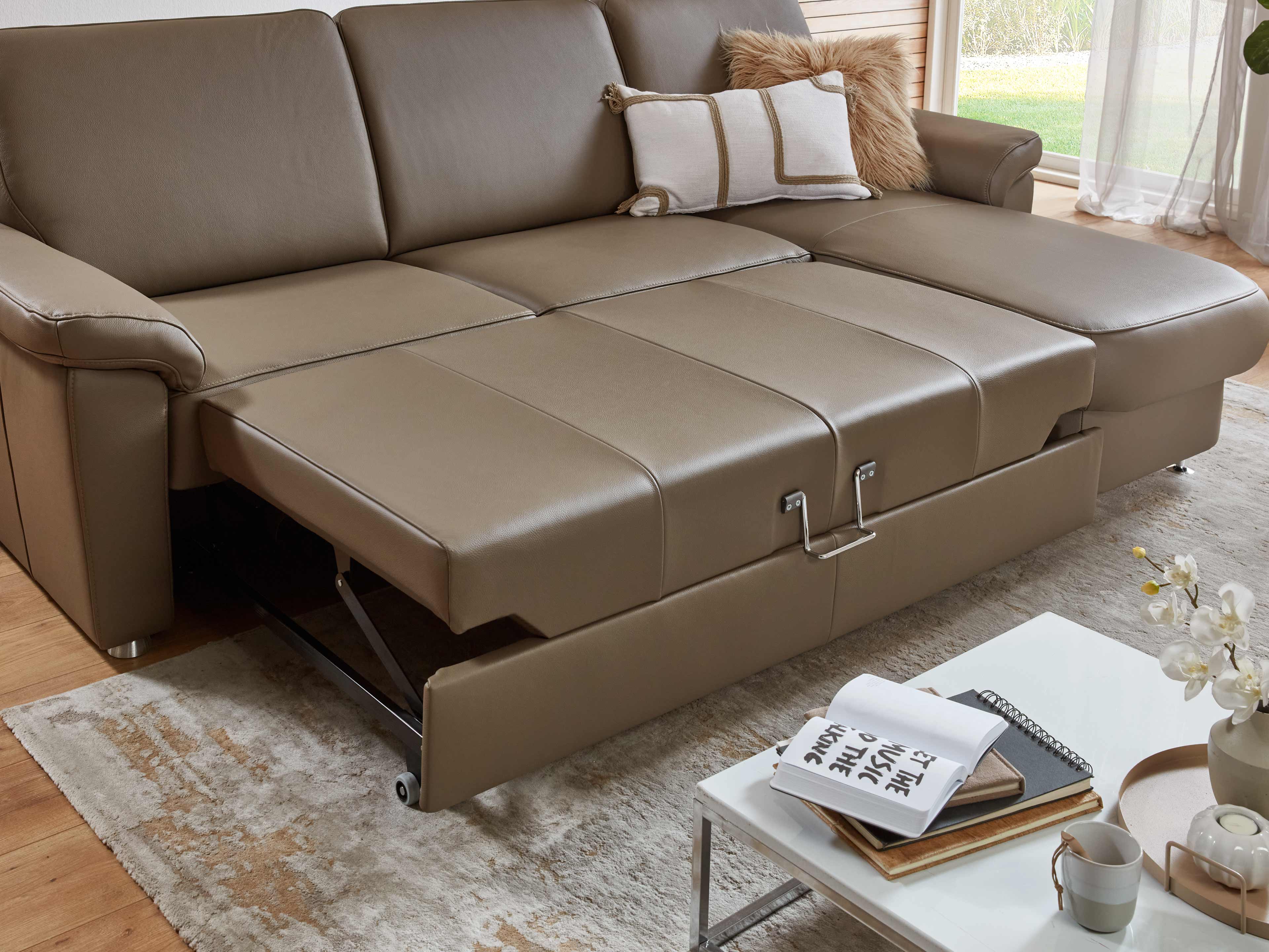 Ecksofa mit Ausziehfunktion aus braunem Leder, sichtbare Armlehnen und gepolsterte Sitzfläche