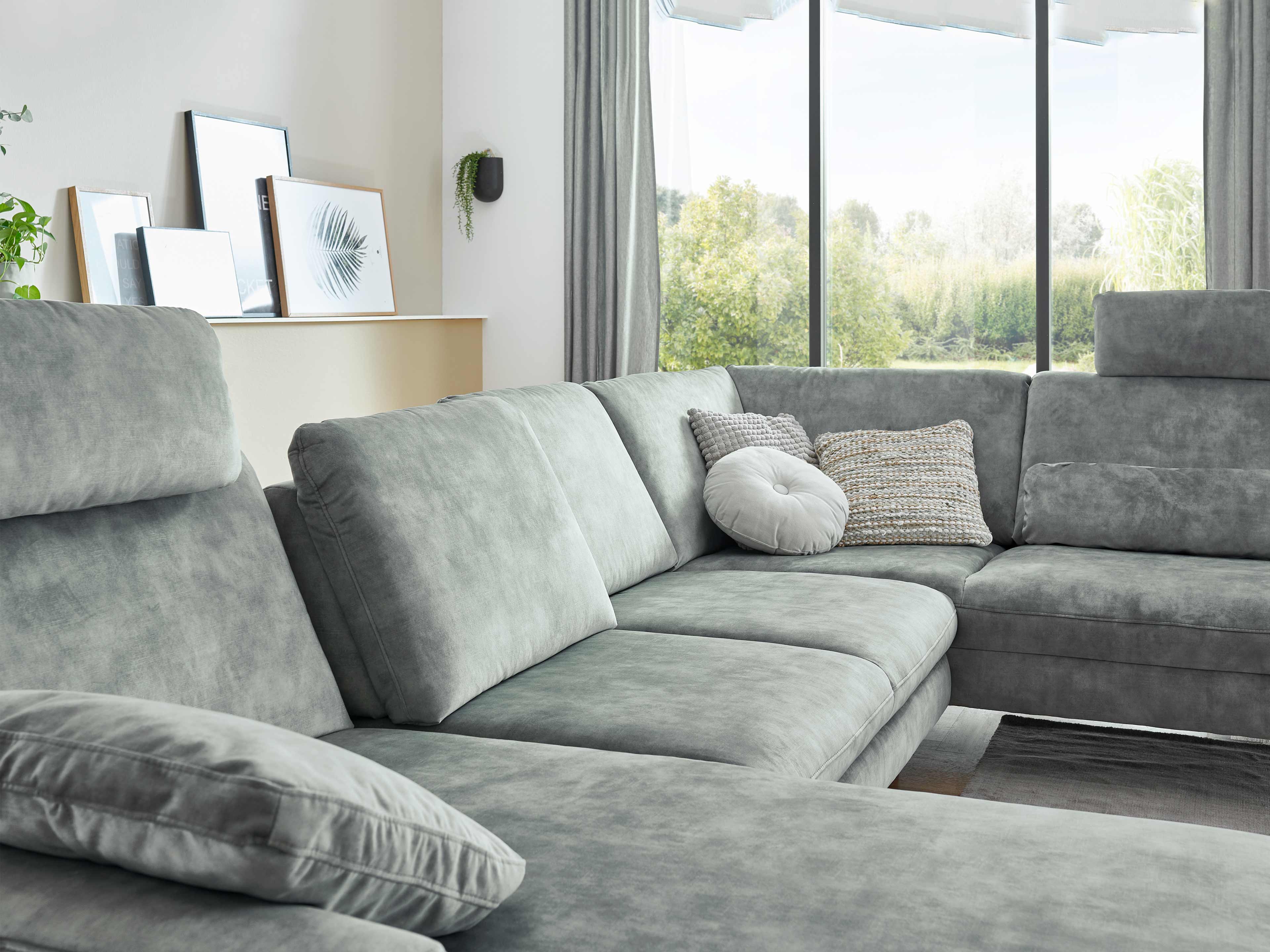 Ecksofa Kabs Polsterwelt aus grauem Stoff mit gepolsterten Rückenlehnen und breiten Sitzflächen