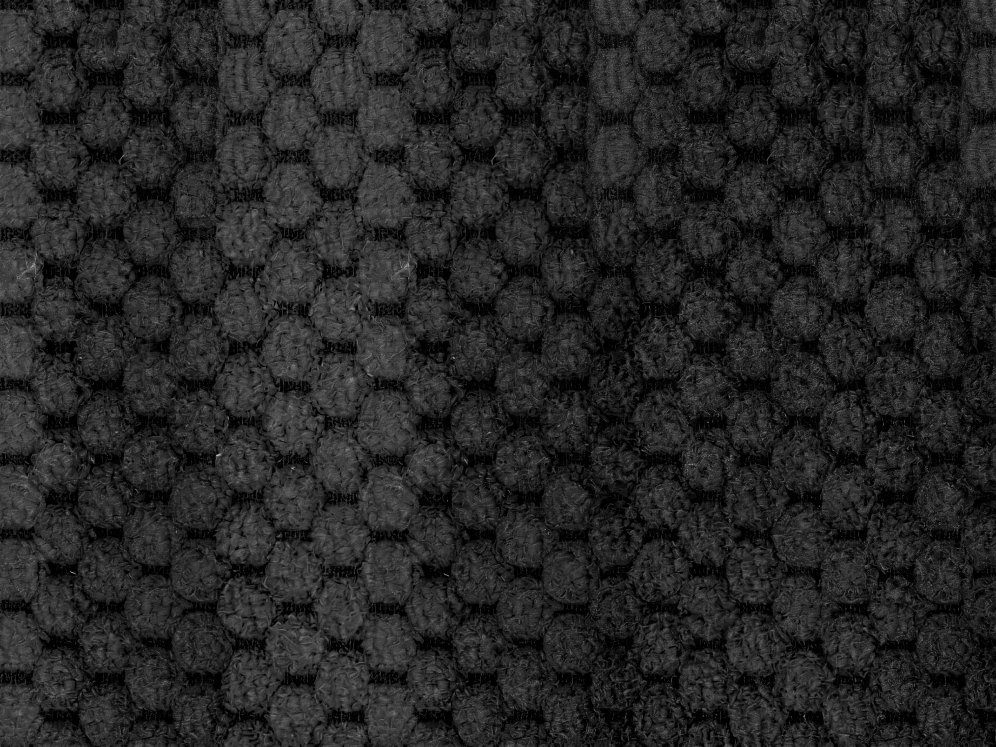 Schwarzer Polsterstoff in Wabenstruktur mit erhabener, runder Oberfläche und sichtbarer Textur