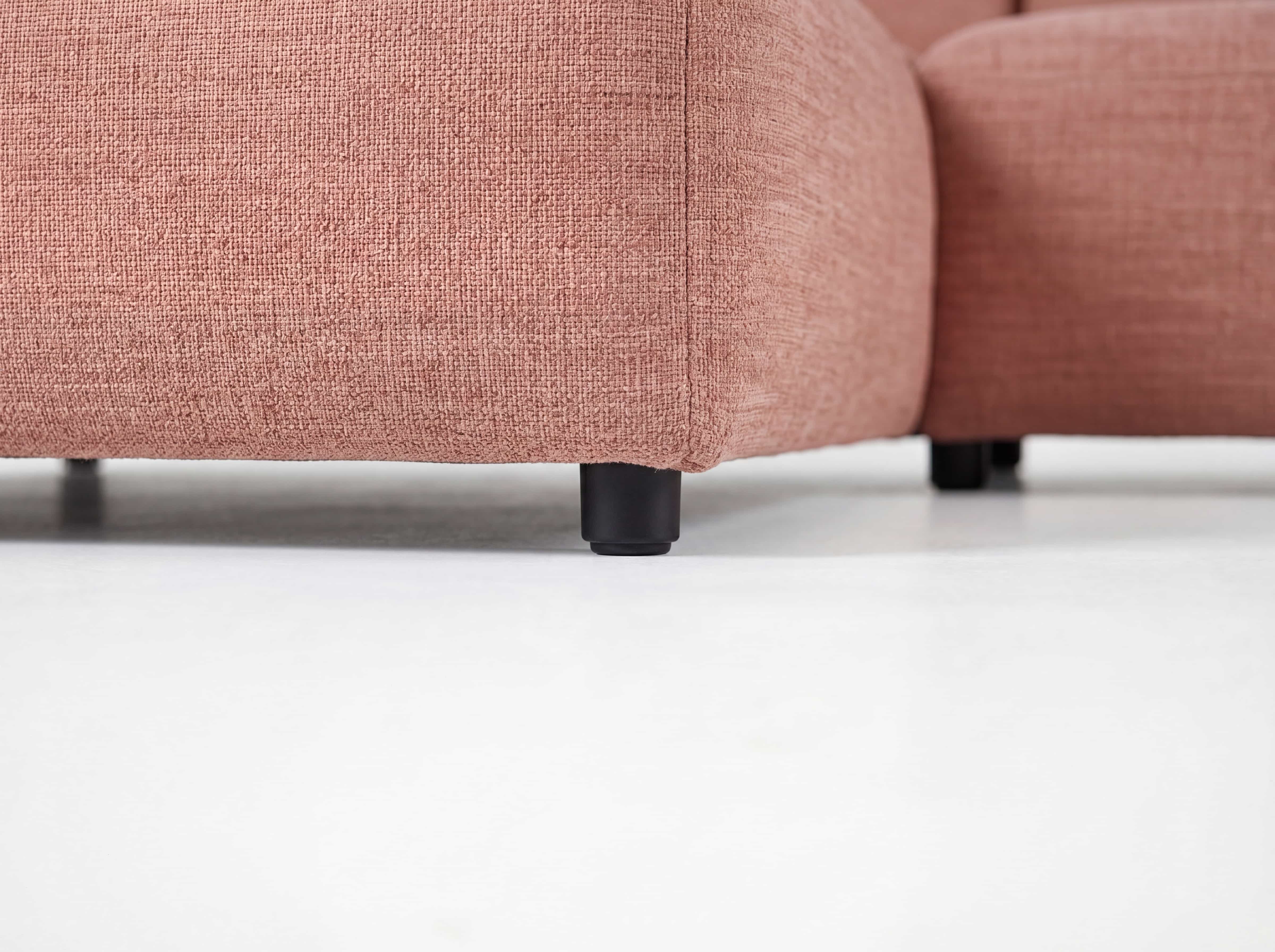 Ecksofa Kabs mit rosa Stoffbezug, abgerundeten Formen und schwarzen, kurzen Sofafüßen