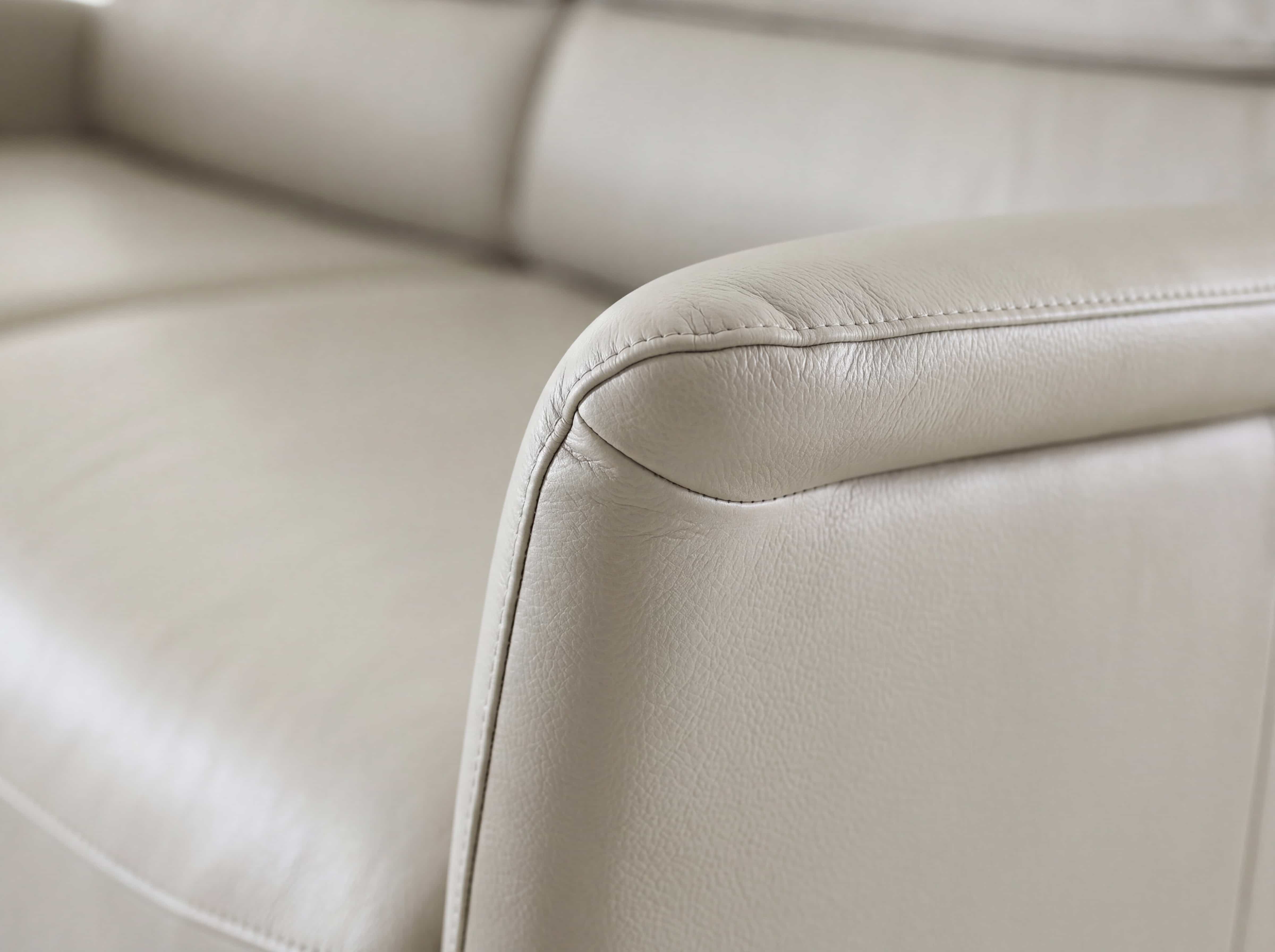 2-Sitzer Sofa mit beigefarbenem Lederbezug und gepolsterter Armlehne in Nahaufnahme